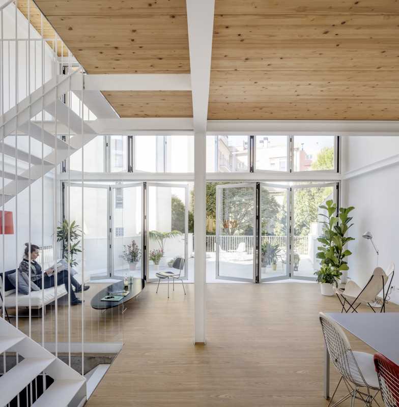 A modern home with a wall of foldable windows that connect the interior with the courtyard outside.