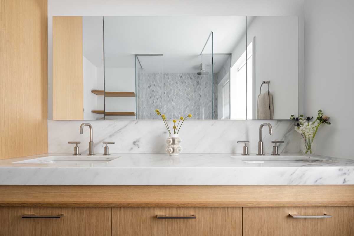 This primary bathroom featuries a glass-enclosed shower, and a double vanity.