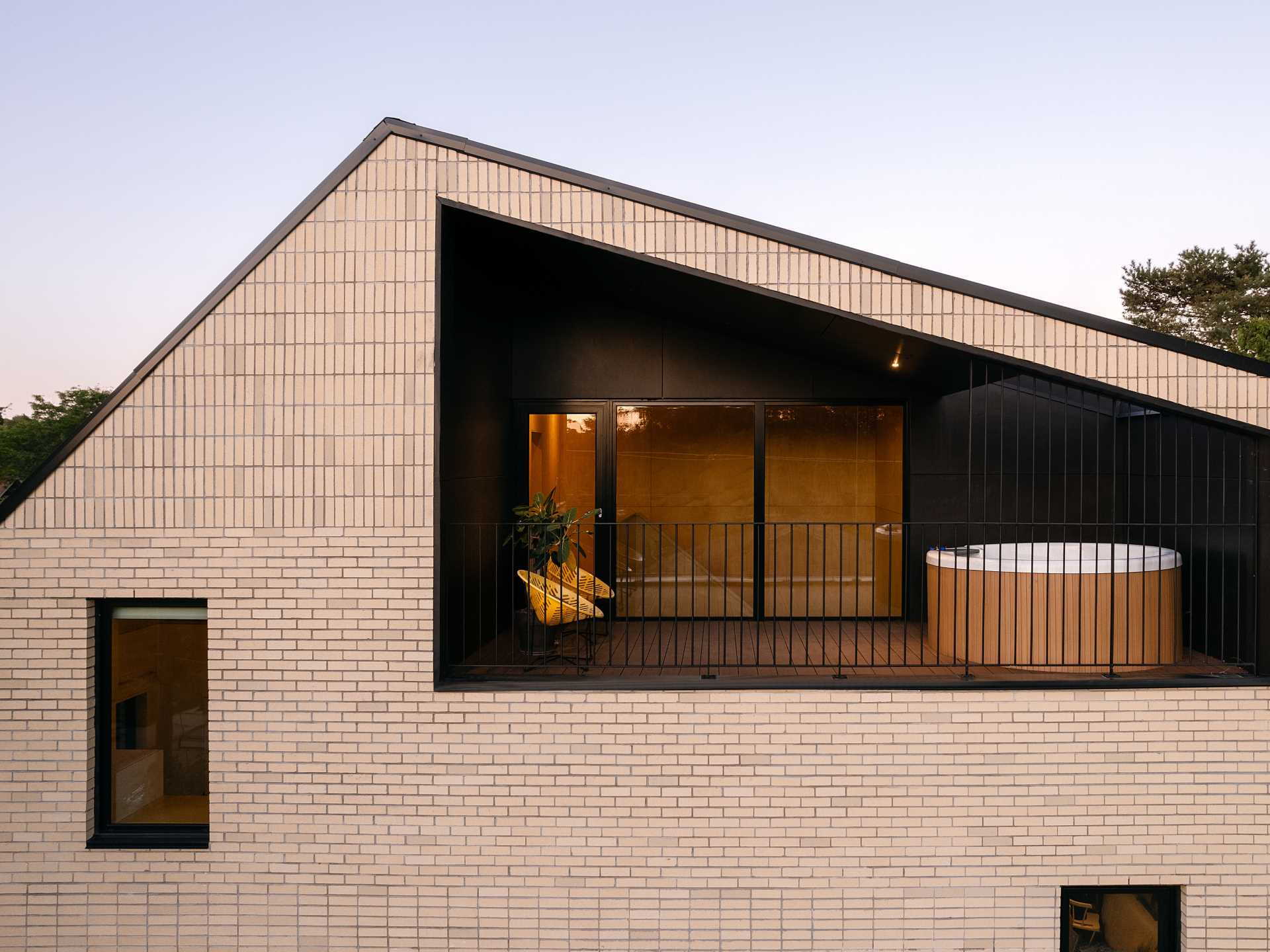 A modern brick home with a partially covered balcony that has a Japanese soaking tub.