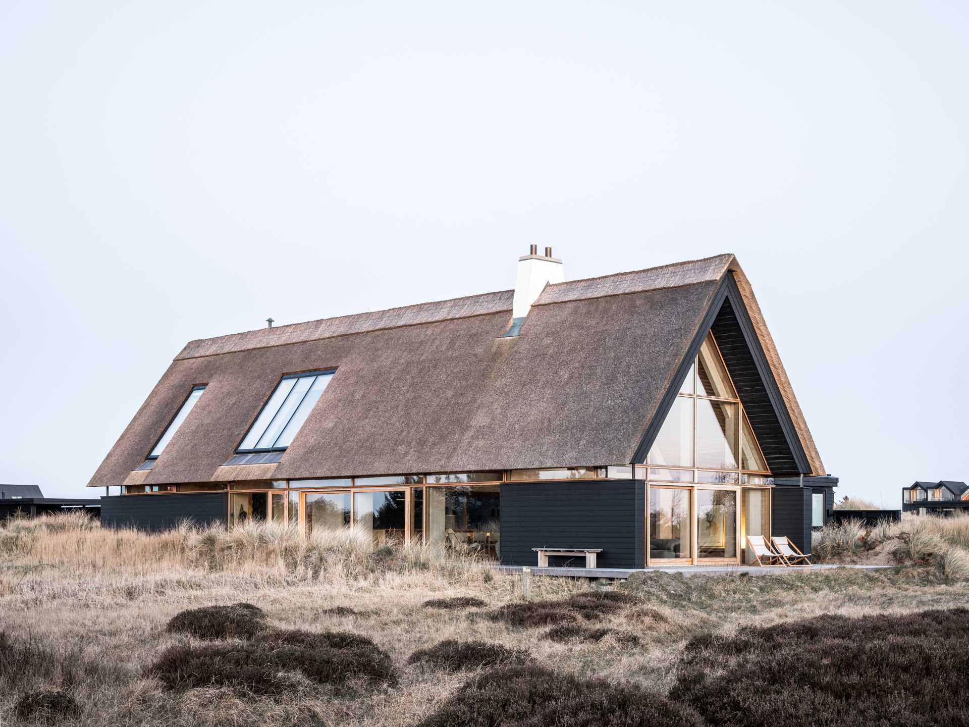 A modern home with black charred wood siding and a thatched roof.