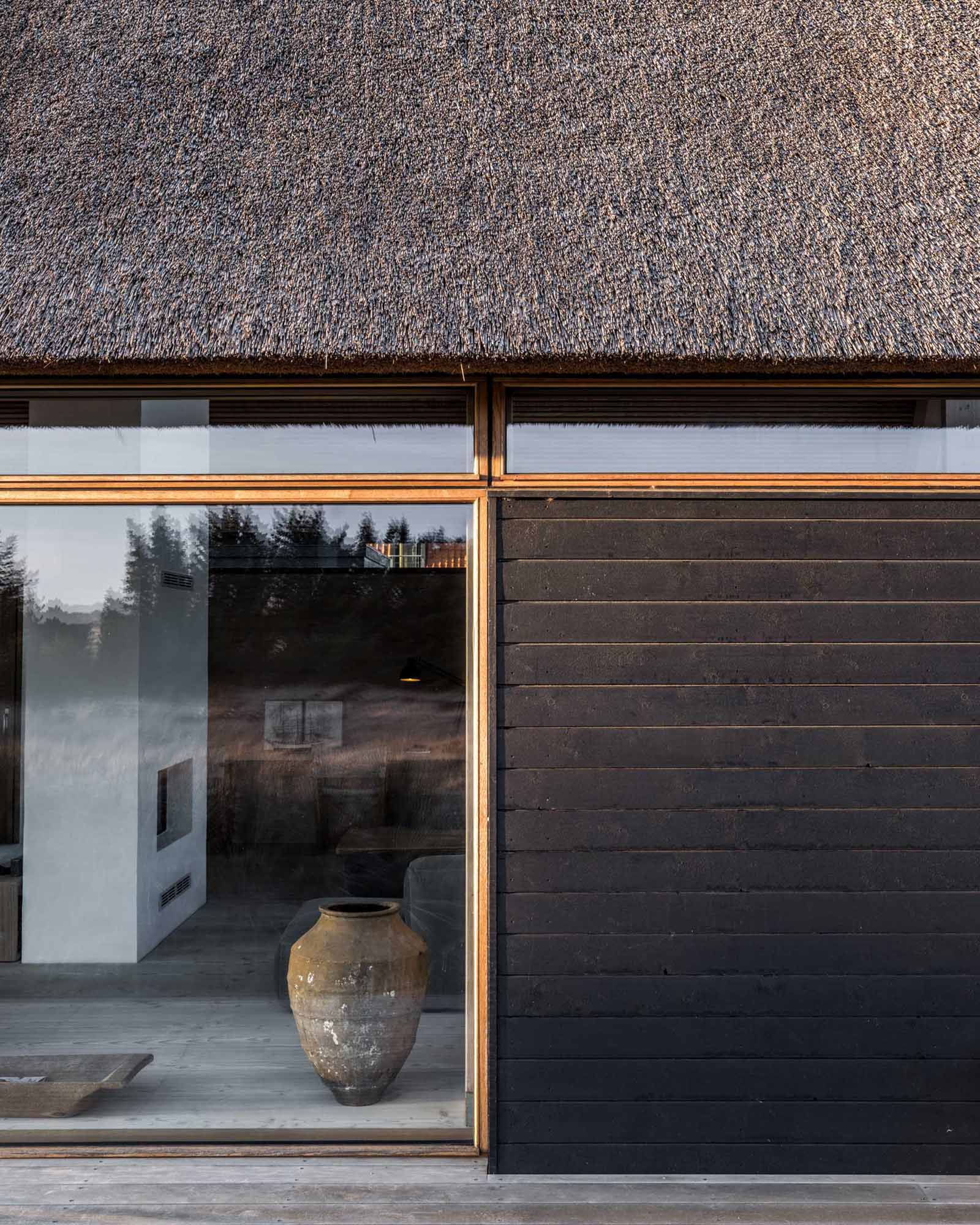 A modern home with black charred wood siding and a thatched roof.