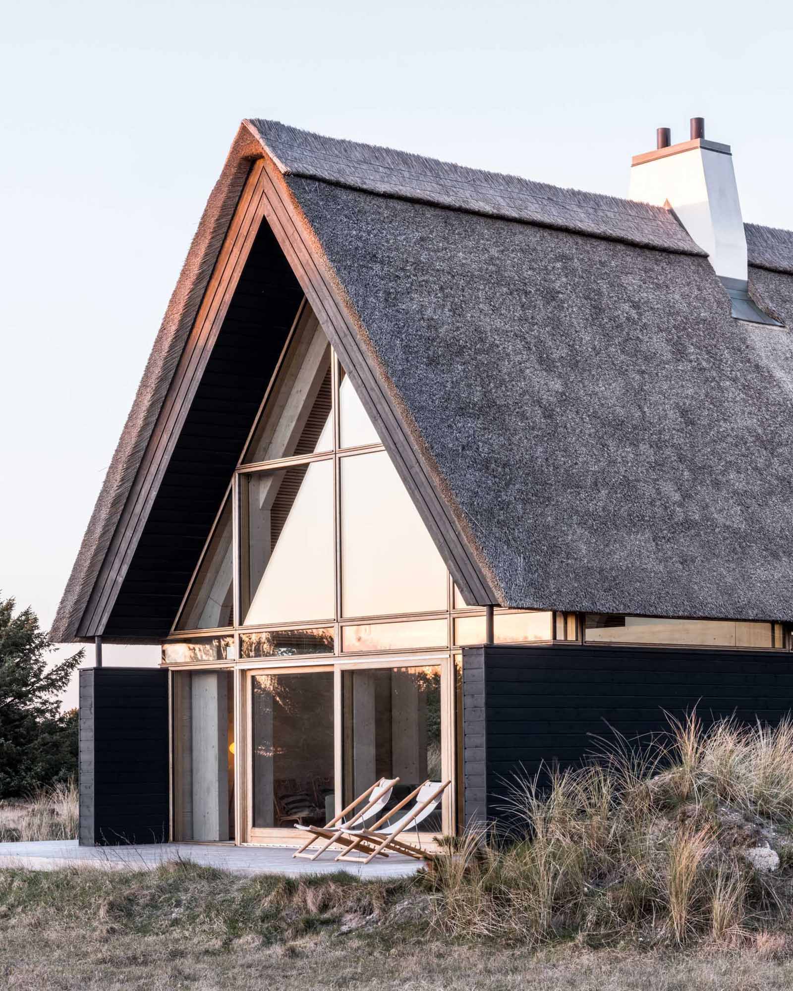 A modern home with black charred wood siding and a thatched roof.