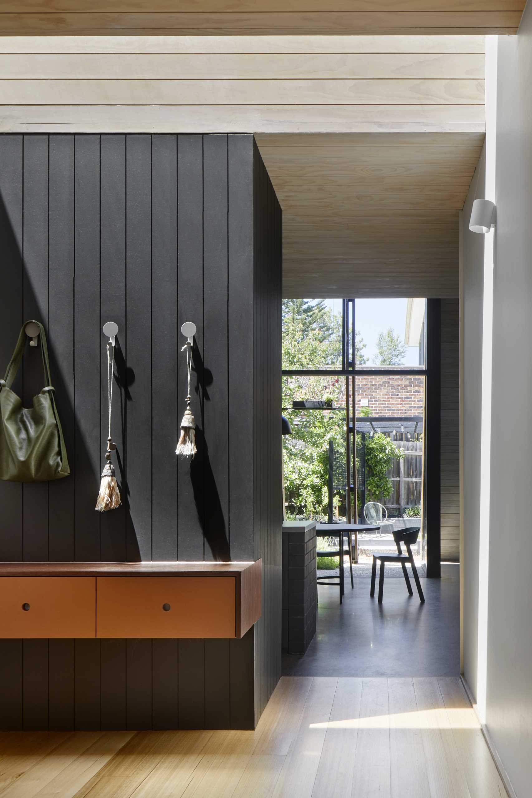 In an open area near the entrance to the home extension includes a floating console with hooks and shelving.