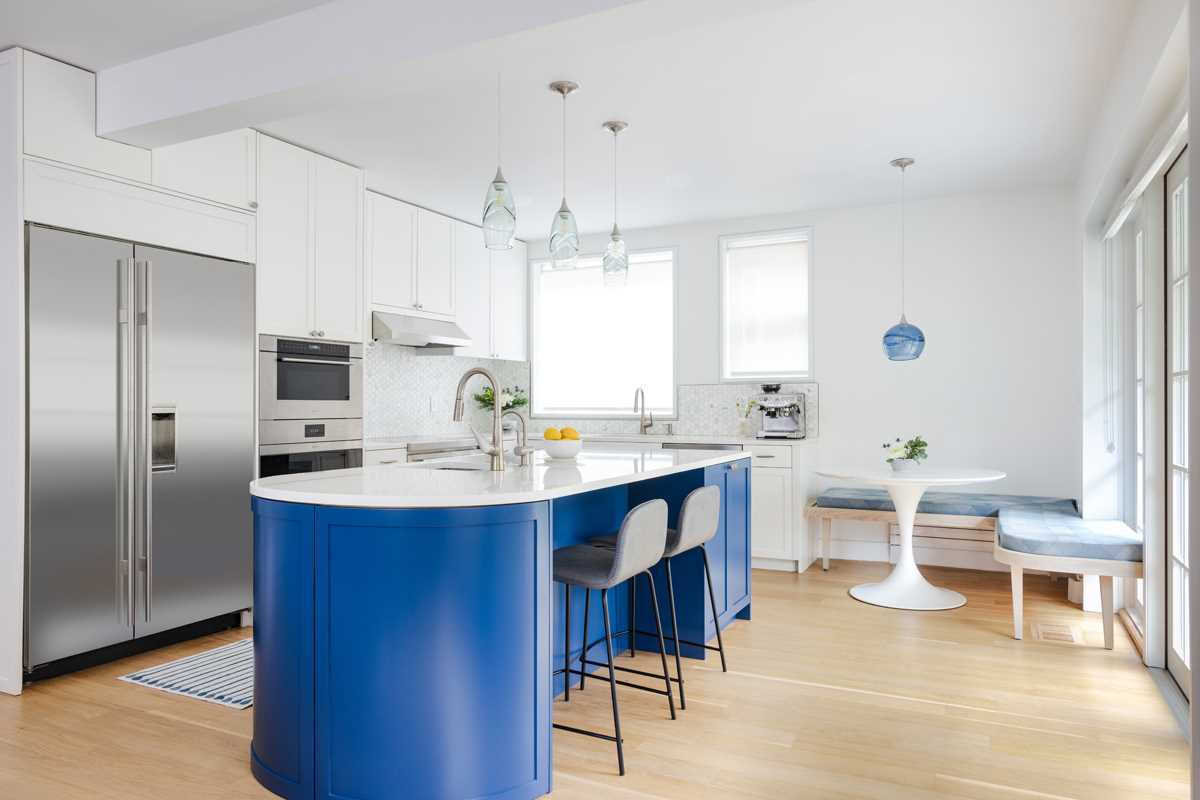 A modern kitchen with a large curved kitchen island with counter seating, and a seating area that wraps around the corner.