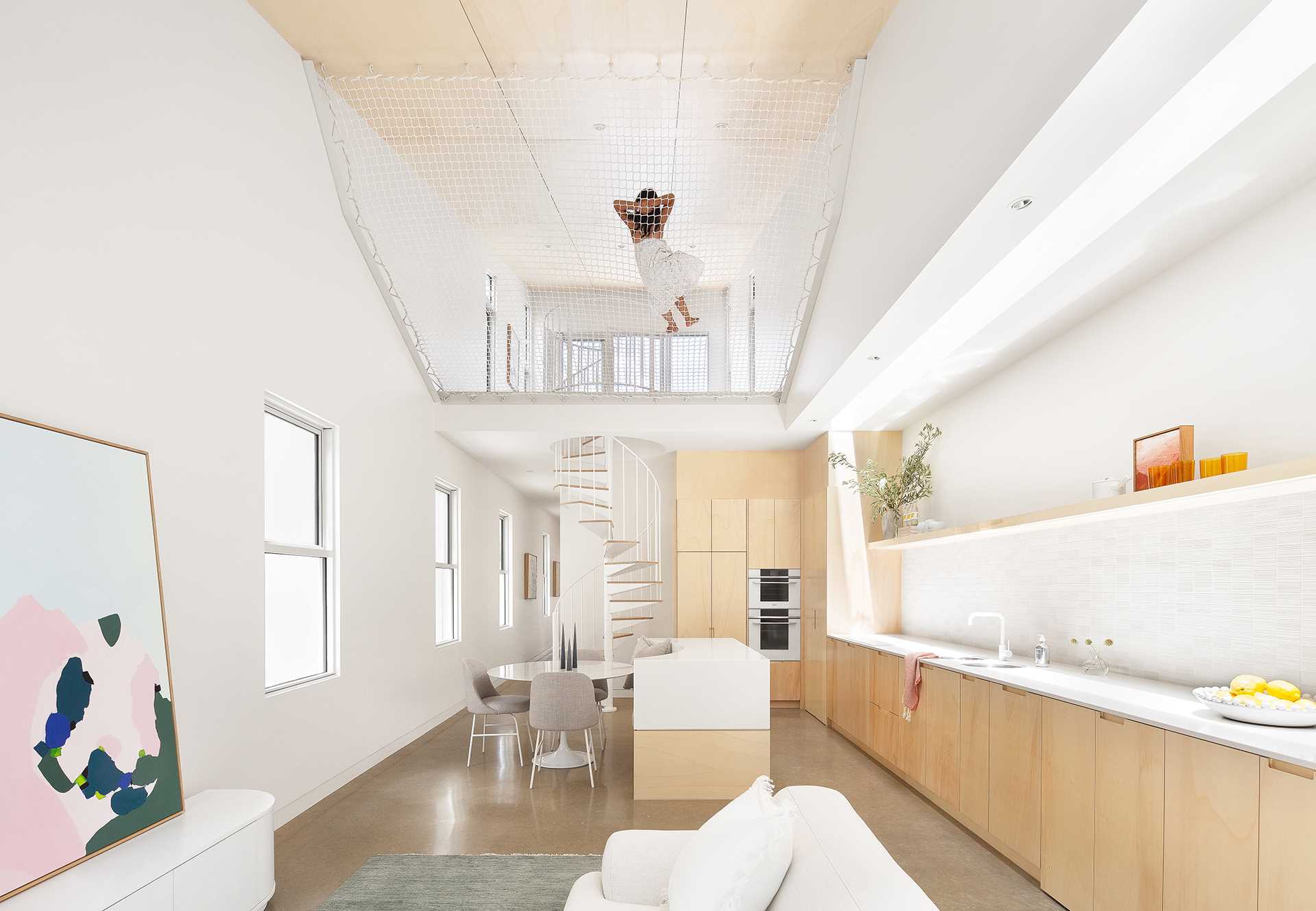 A modern wood and white kitchen with a floating shelf includes an island with built-in seating for the dining area.