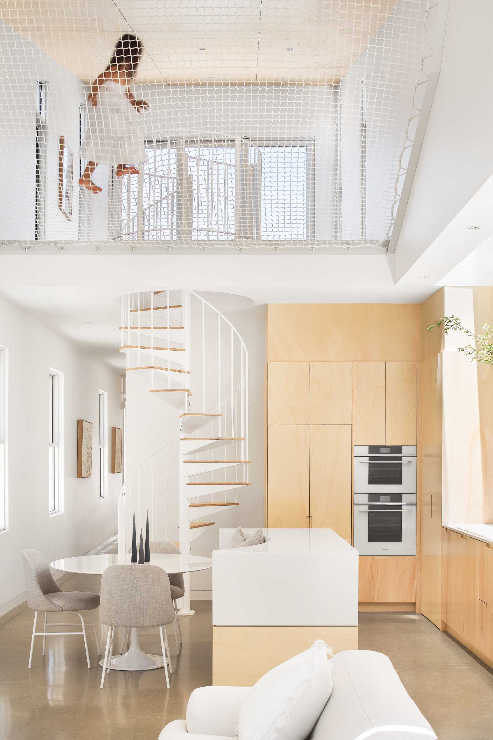 A modern wood and white kitchen with a floating shelf includes an island with built-in seating for the dining area.