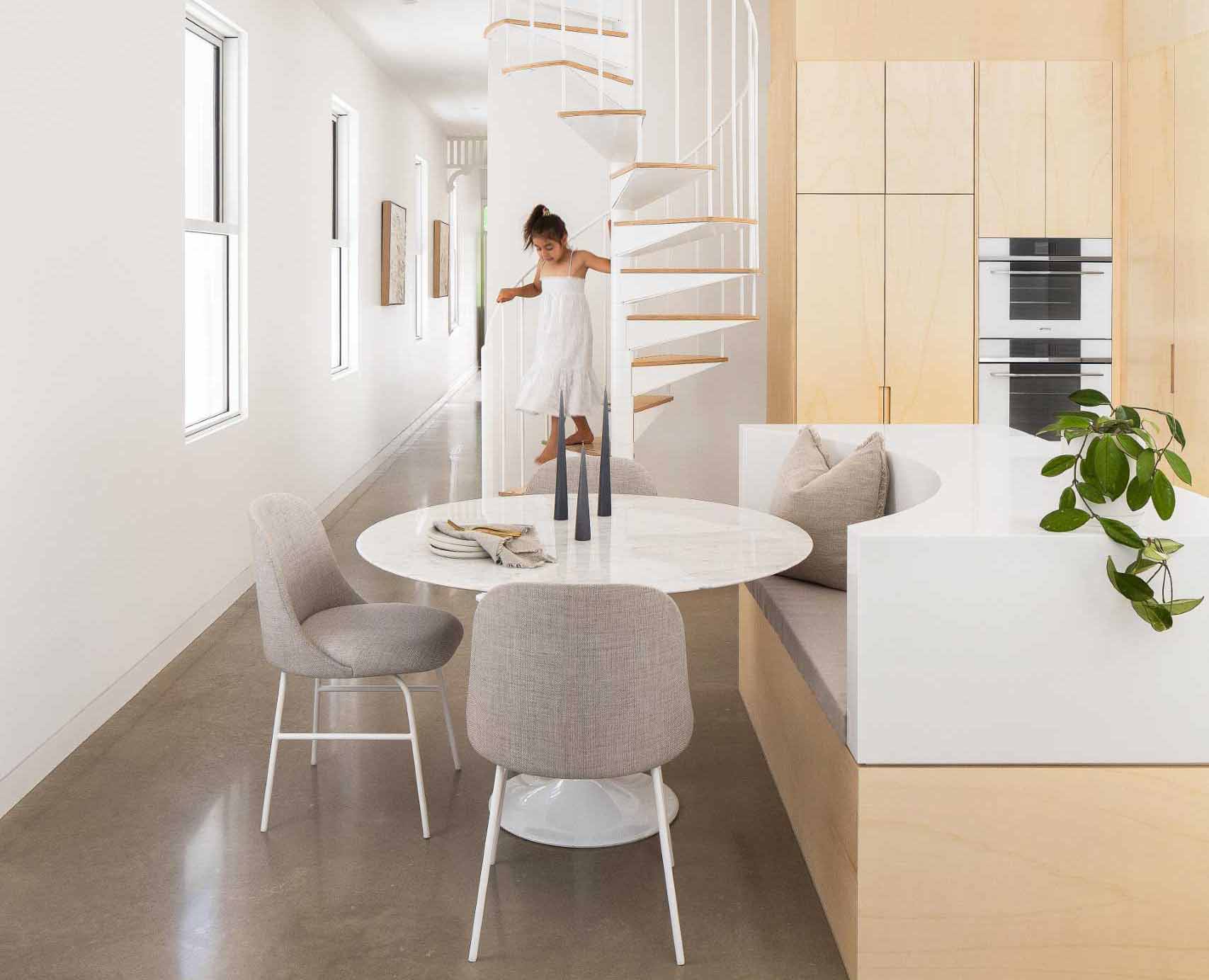A modern wood and white kitchen with a floating shelf includes an island with built-in seating for the dining area.