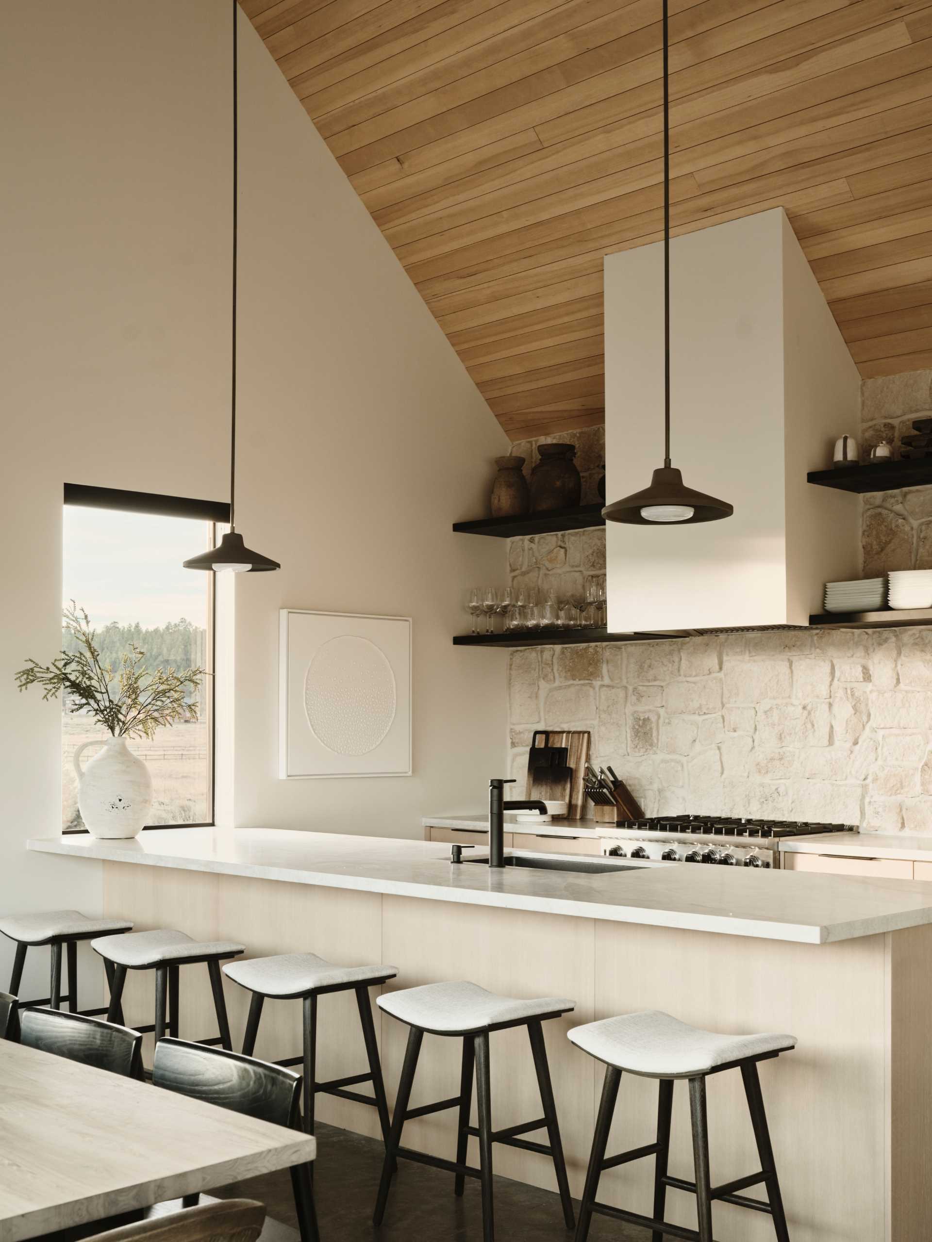 In this kitchen, a stone wall provides a backdrop for the stove and open shelving.