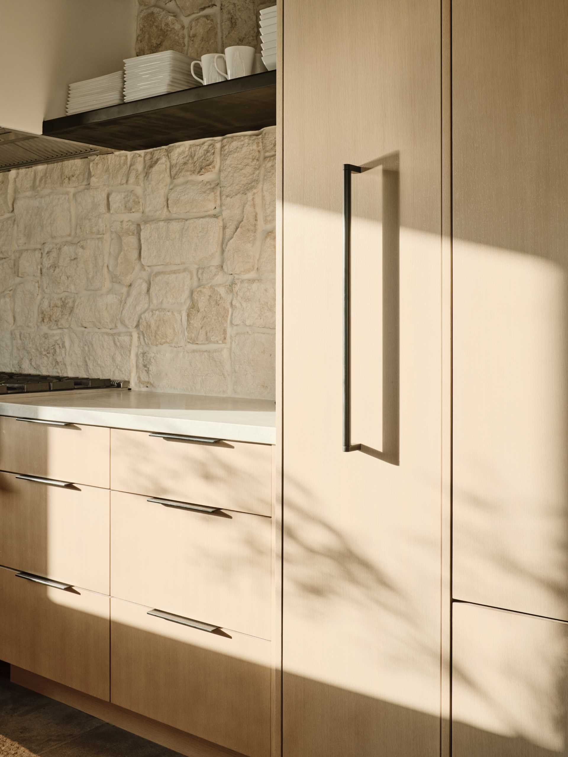 In this kitchen, a stone wall provides a backdrop for the stove and open shelving.