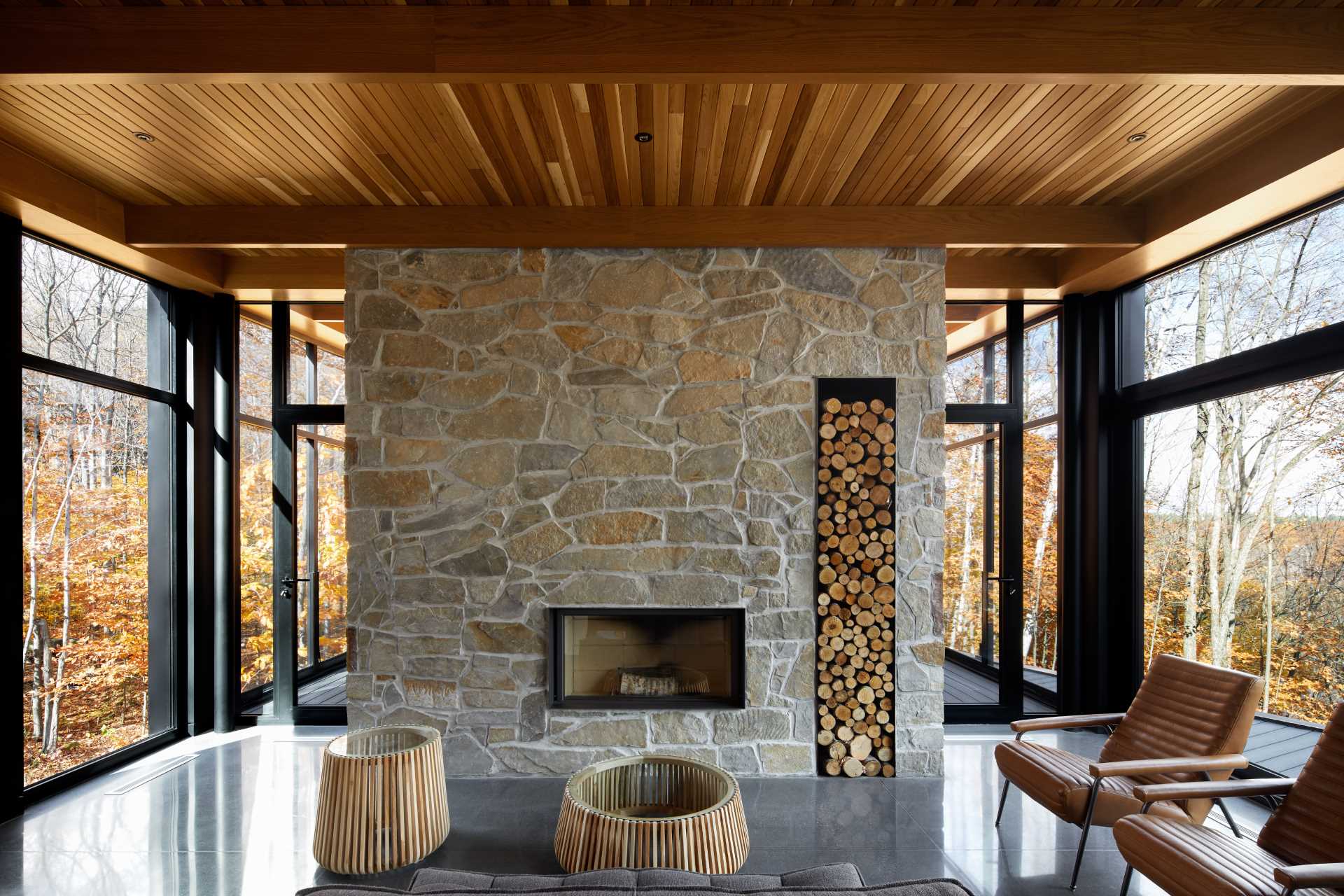 A sitting area with a wood-burning fireplace integrated into a massive stone wall soothes the room and offers a warm contrast to the raw materials of concrete, steel, and glass.