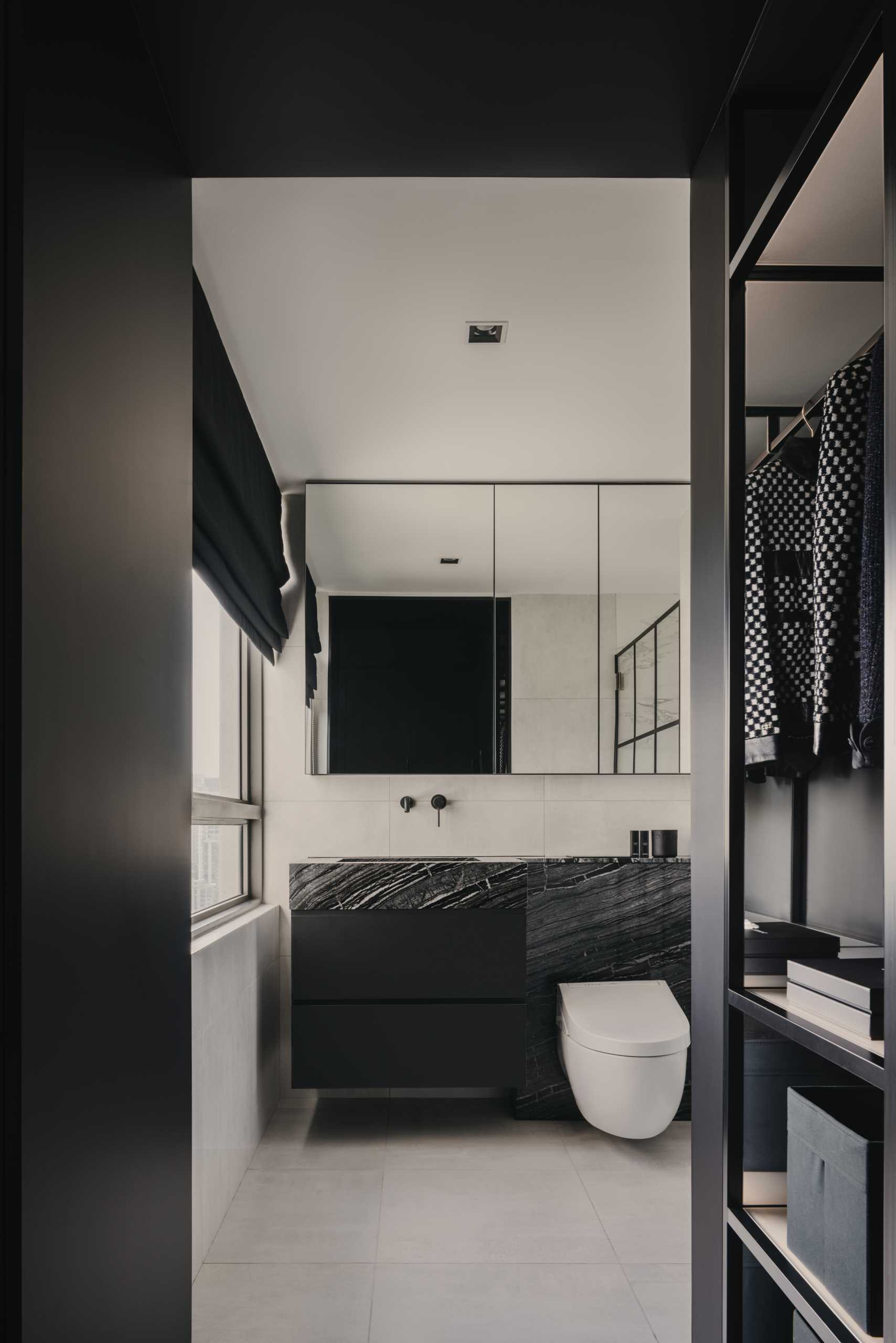 A modern bathroom with a monochrome theme, includes a black vanity, a stone countertop, and a s،wer with black accents.