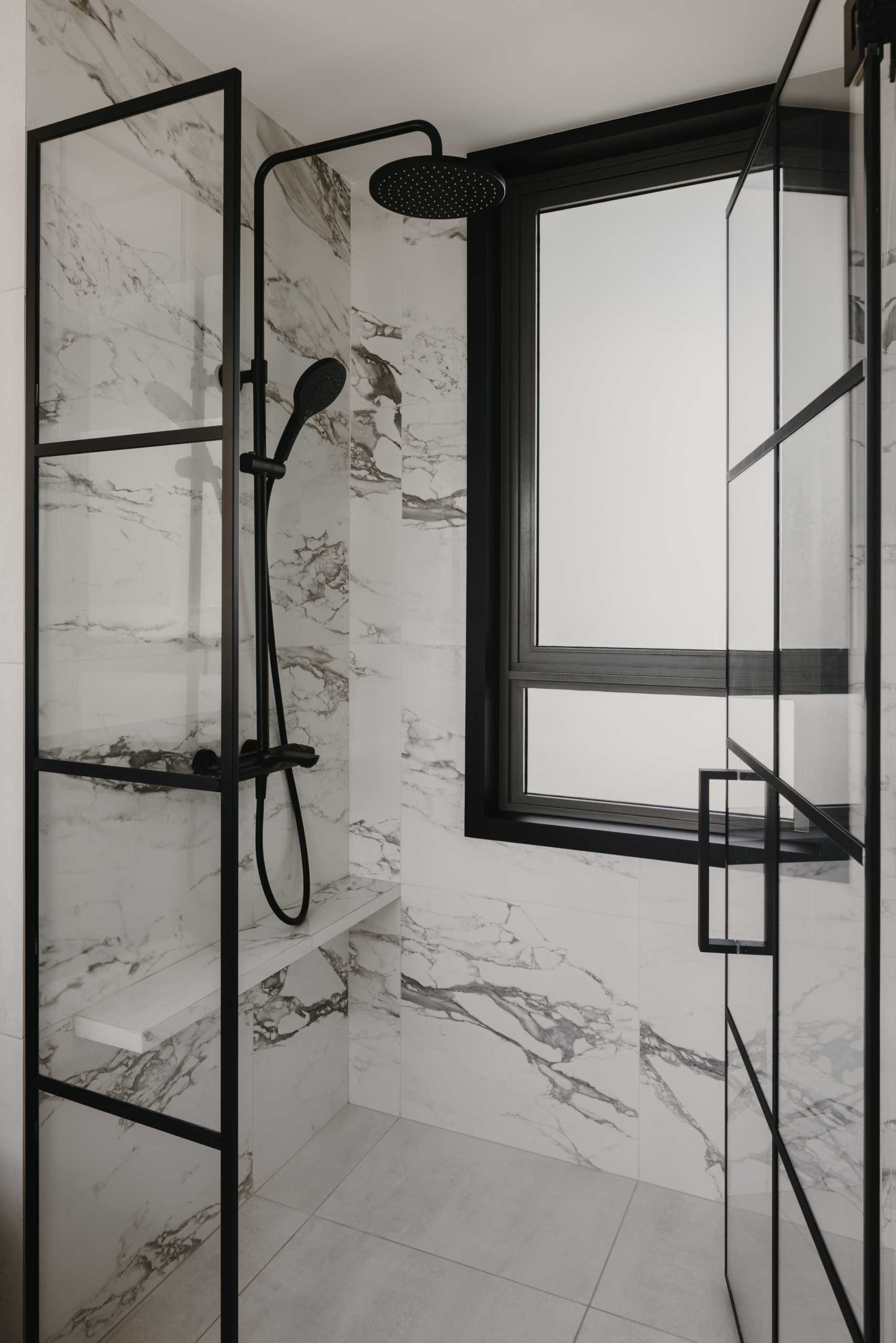 A modern bathroom with a monochrome theme, includes a black vanity, a stone countertop, and a shower with black accents.