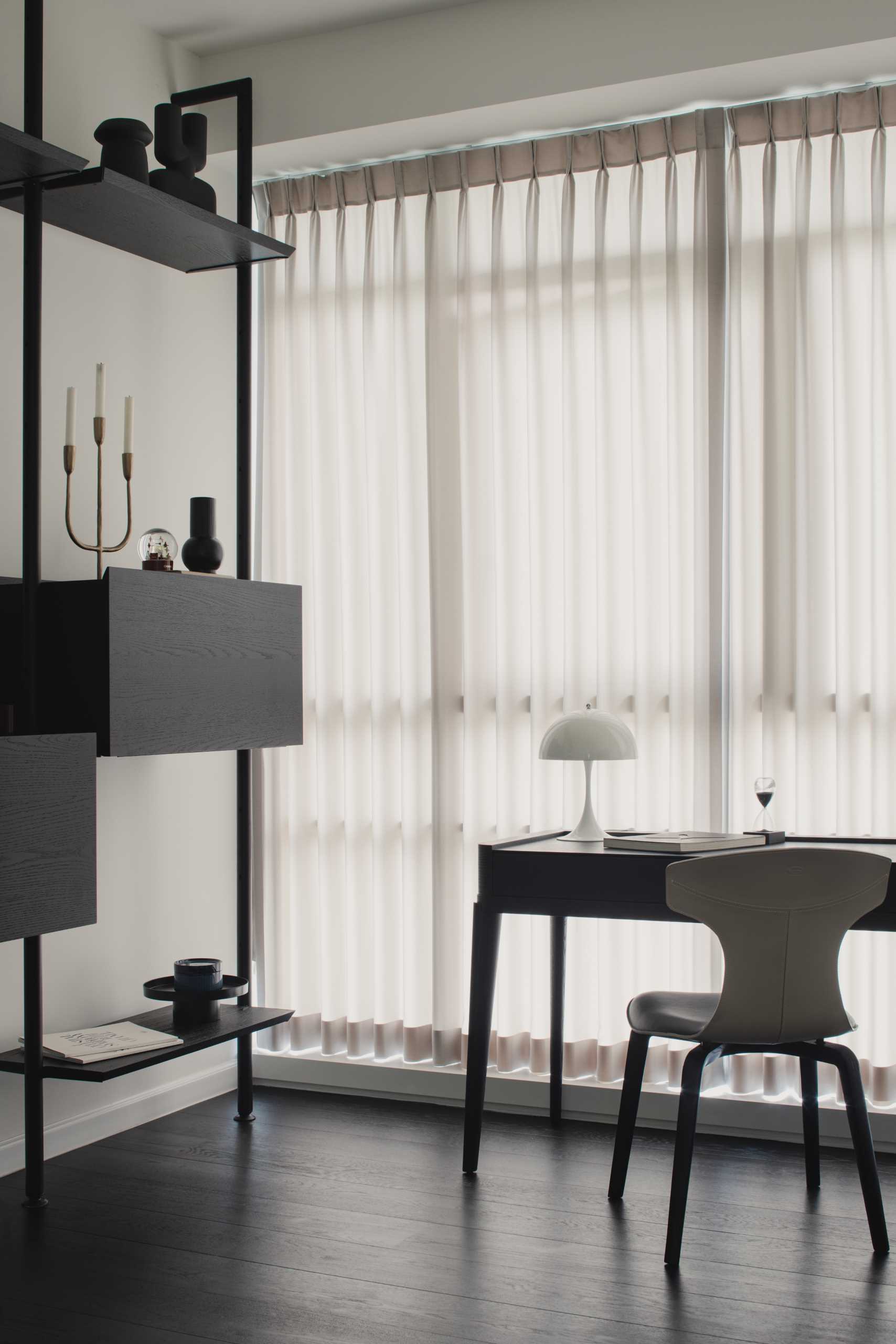 In this monochrome home office, there's a desk by the window, while a shelving unit along the wall showcases additional decorative items and also provides some cabinetry for hidden storage.