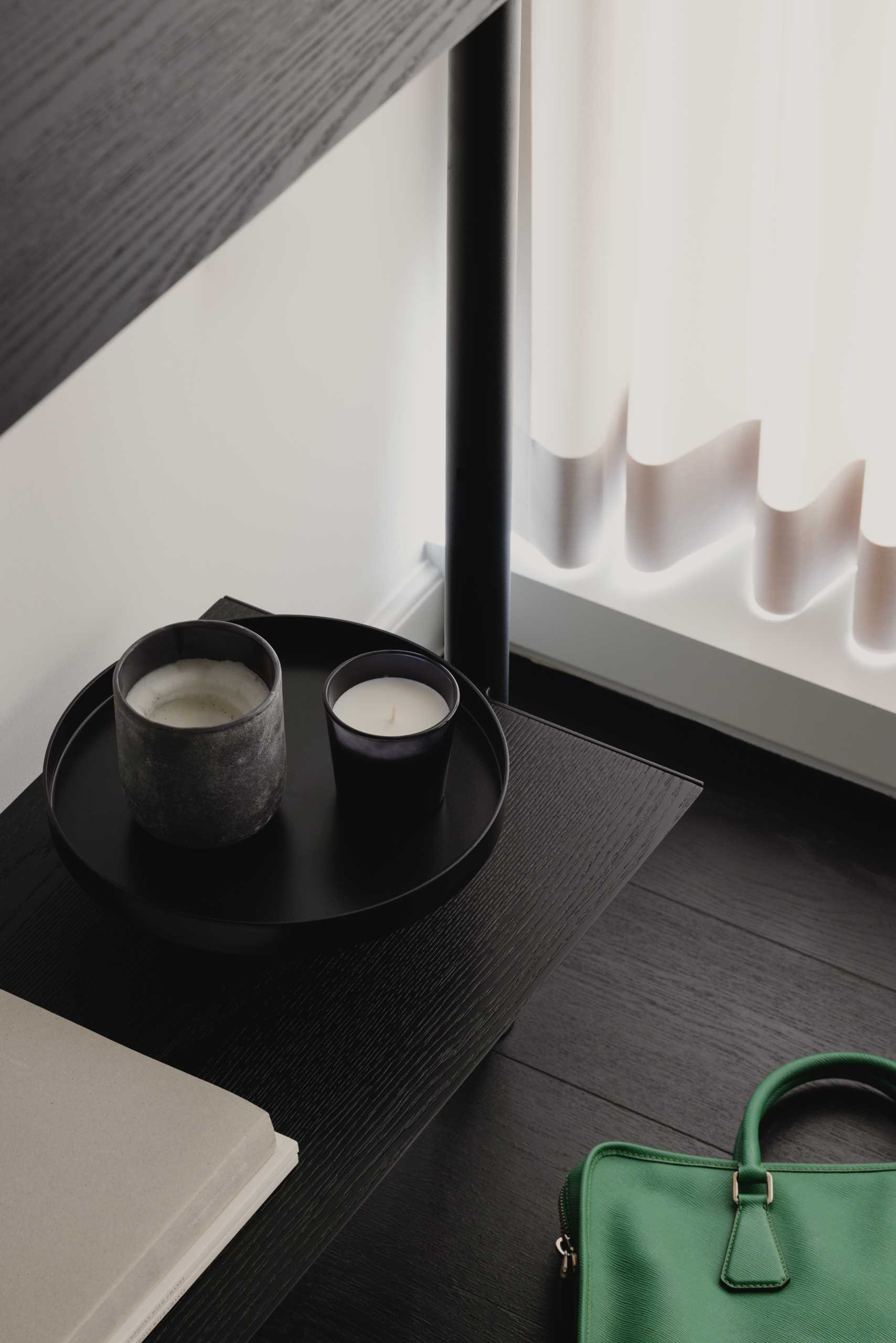 In this monochrome home office, there's a desk by the window, while a shelving unit along the wall showcases additional decorative items and also provides some cabinetry for hidden storage.