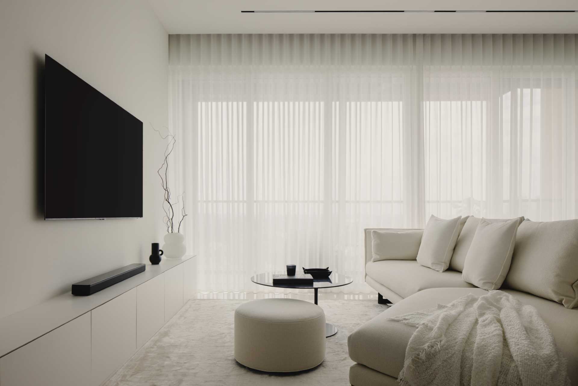 This monochrome living room strikes a balance of light and dark, where a white couch with a matching throw blanket is paired with a black coffee table and TV.