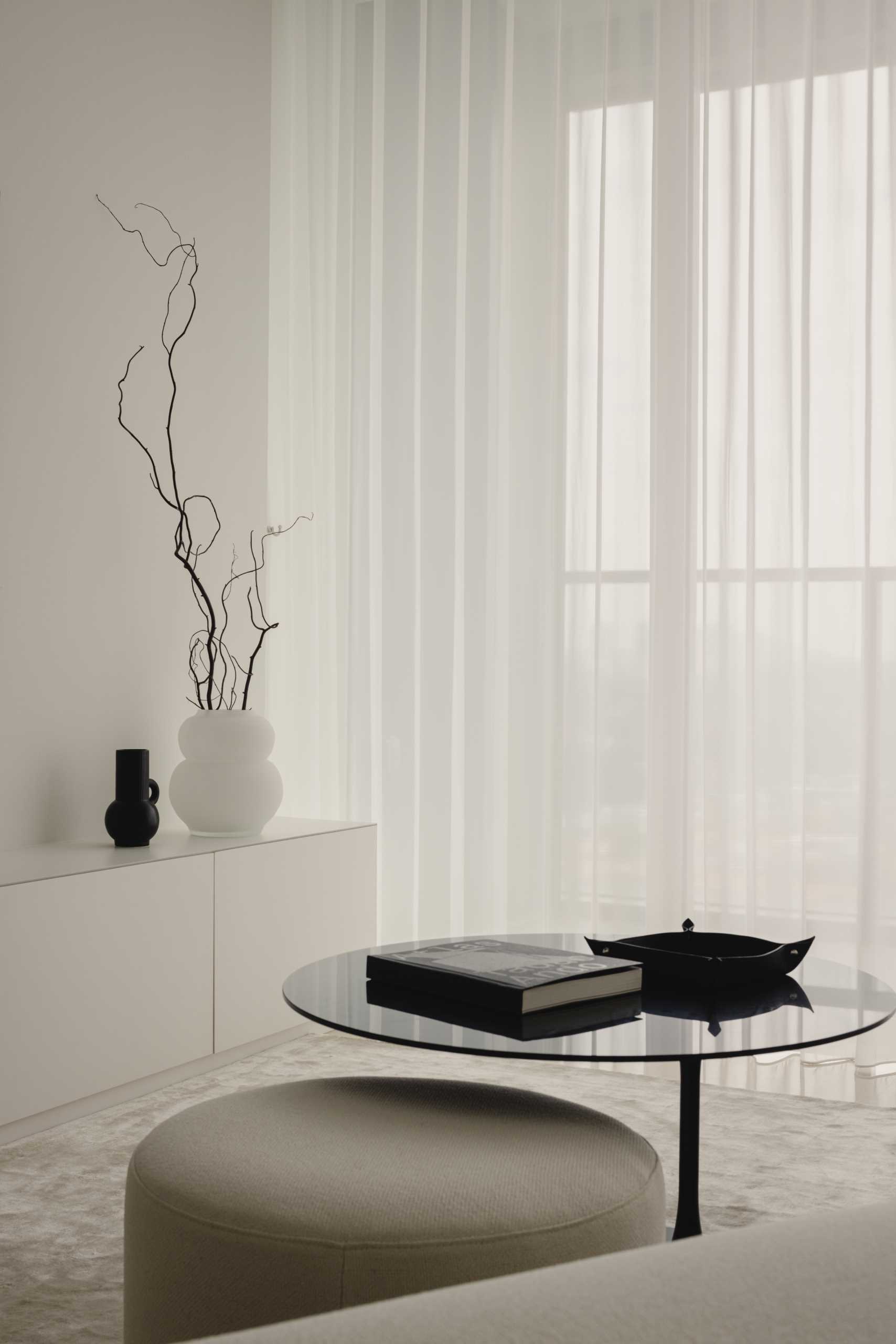 This monochrome living room strikes a balance of light and dark, where a white couch with a matching throw blanket is paired with a black coffee table and TV.