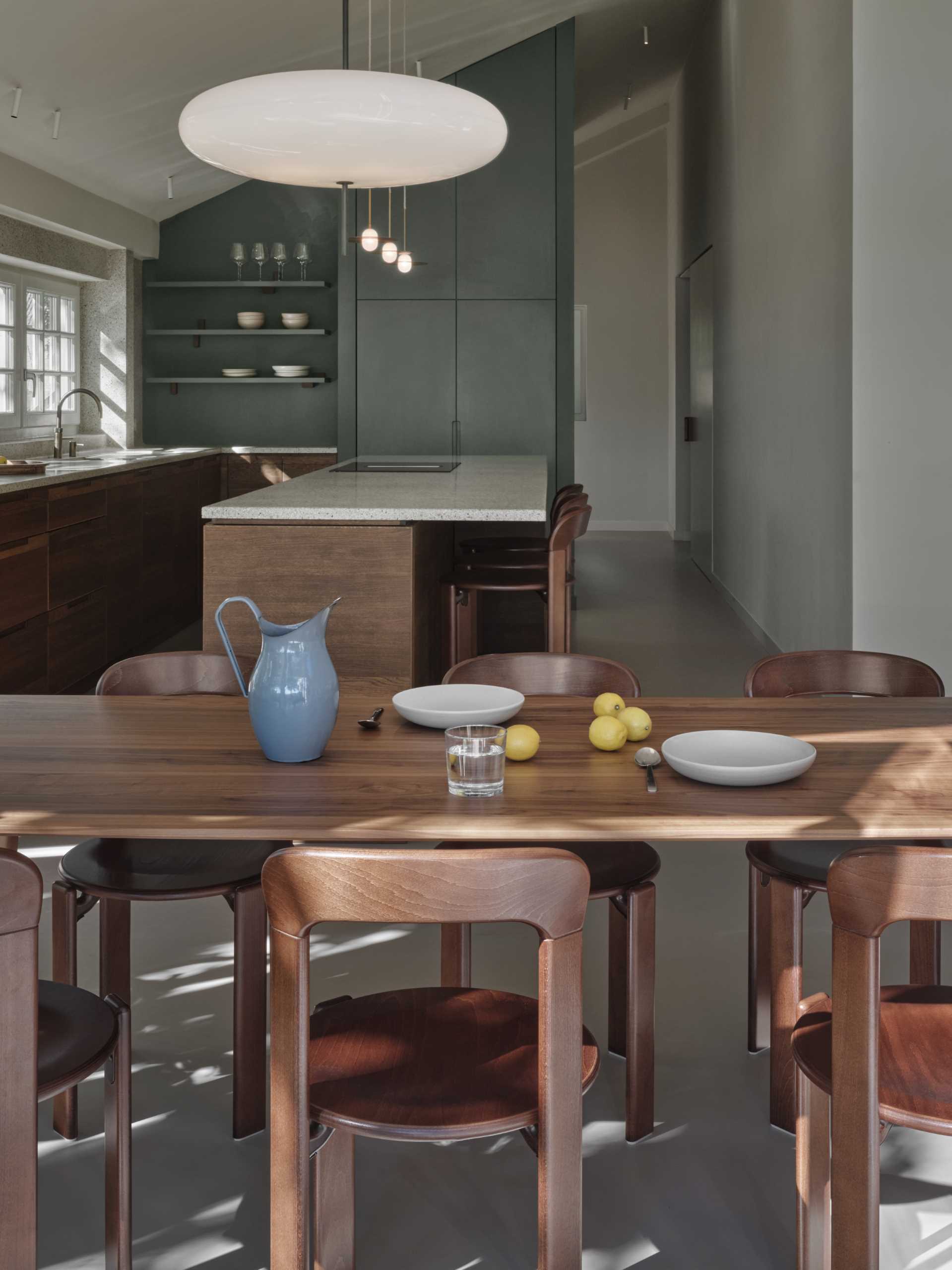 This open plan dining area includes a wood table and matching chairs that complement the nearby kitchen cabinets.