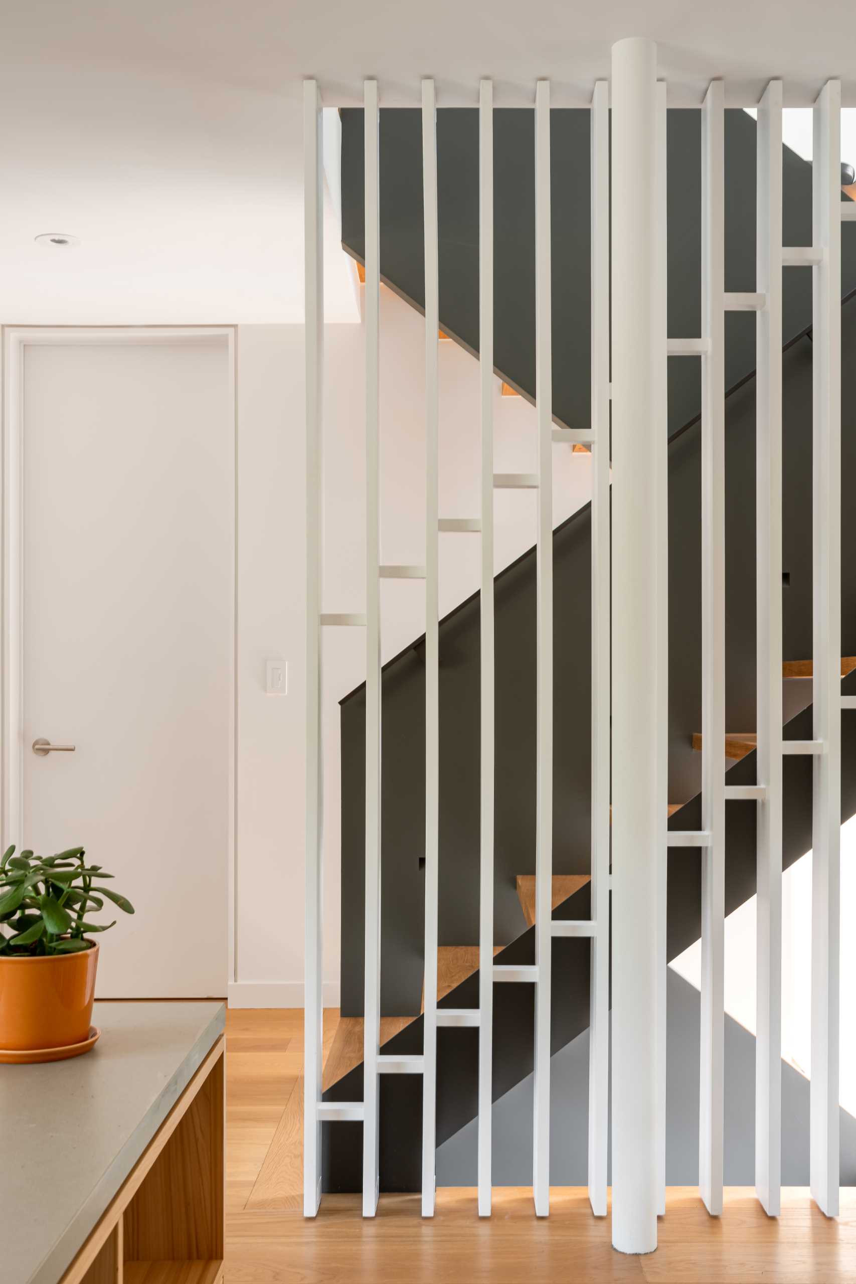 Modern black and wood stairs with a white partition wall.