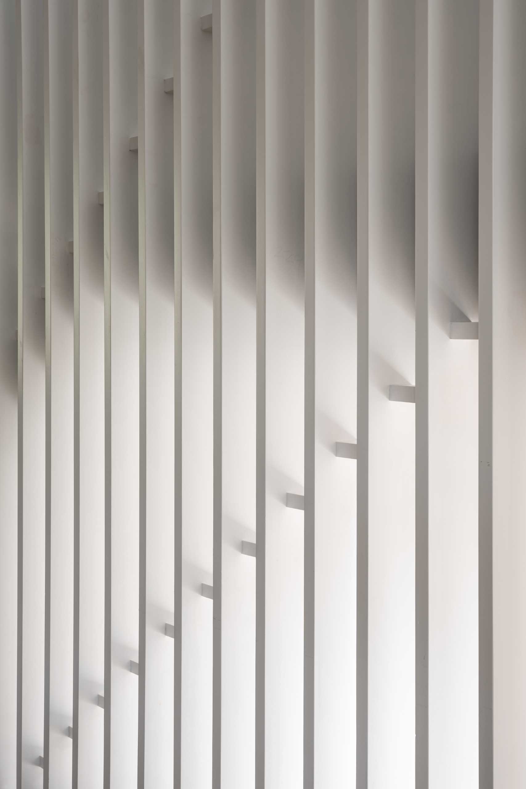 Modern black and wood stairs with a white partition wall.