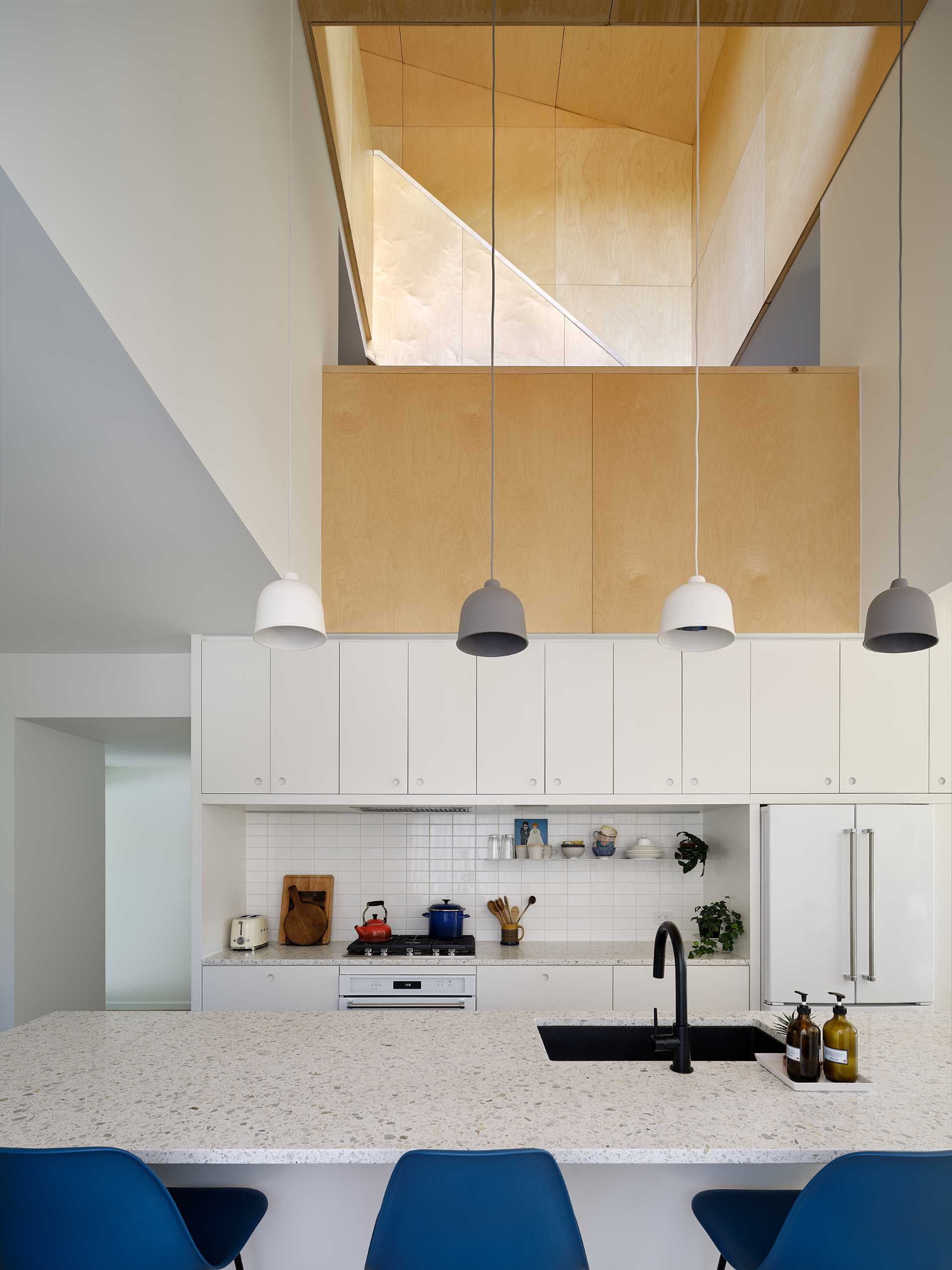 The interior of this home is a casual and affordable palette of natural materials for an anti-museum aesthetic, with recycled strip plank wood flooring, Baltic birch paneling, terrazzo, and concrete.