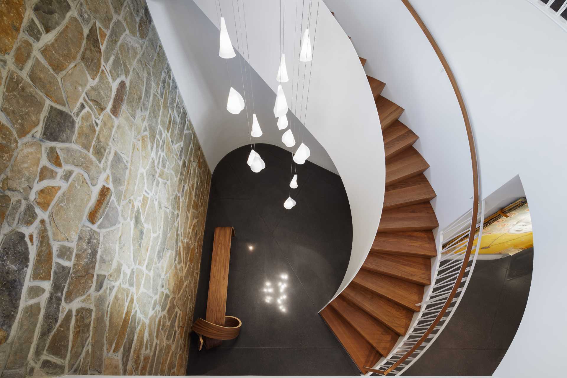 The staircase wraps around cascading pendant fixtures and directs attention towards the upstairs living areas.
