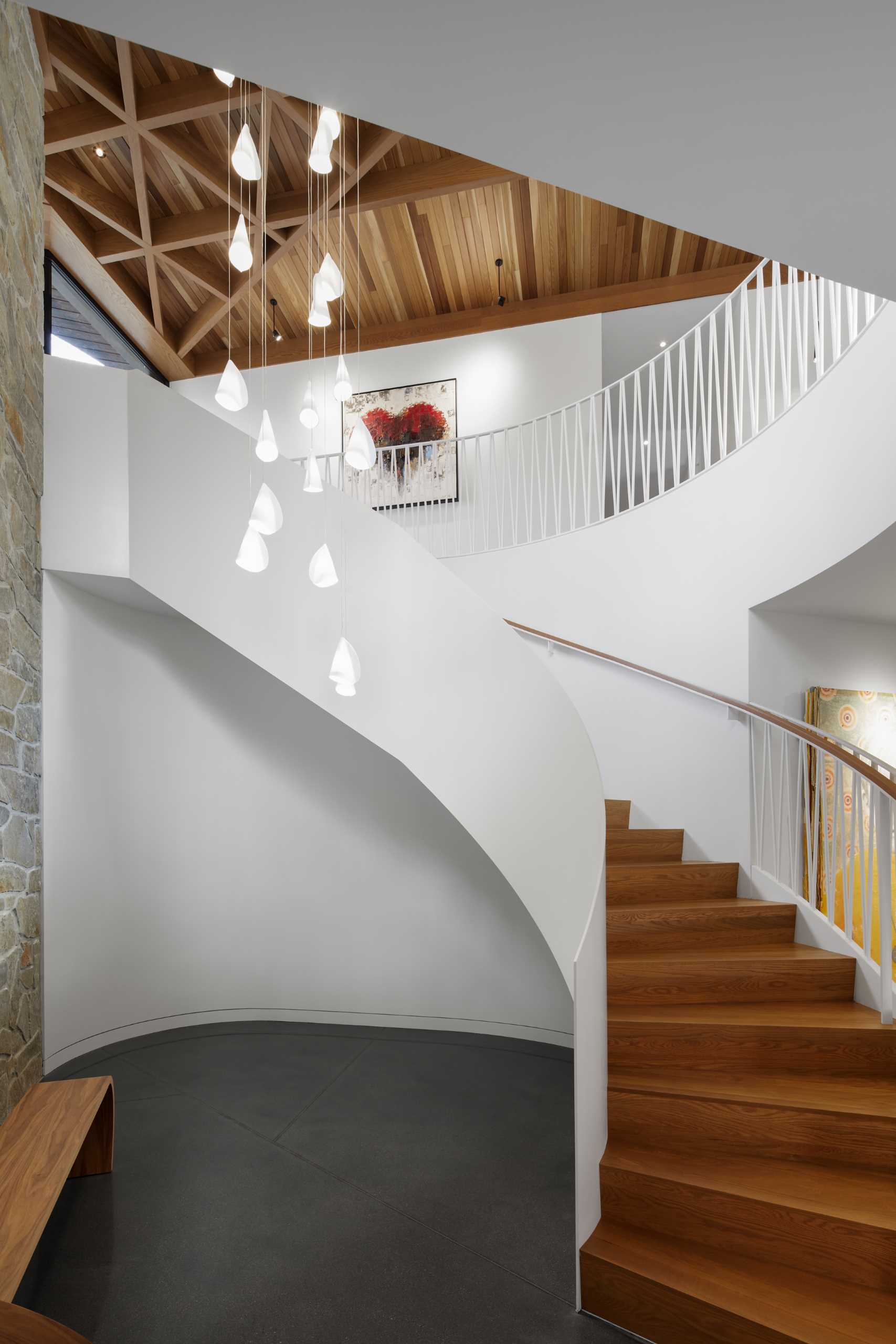 The staircase wraps around cascading pendant fixtures and directs attention towards the upstairs living areas.