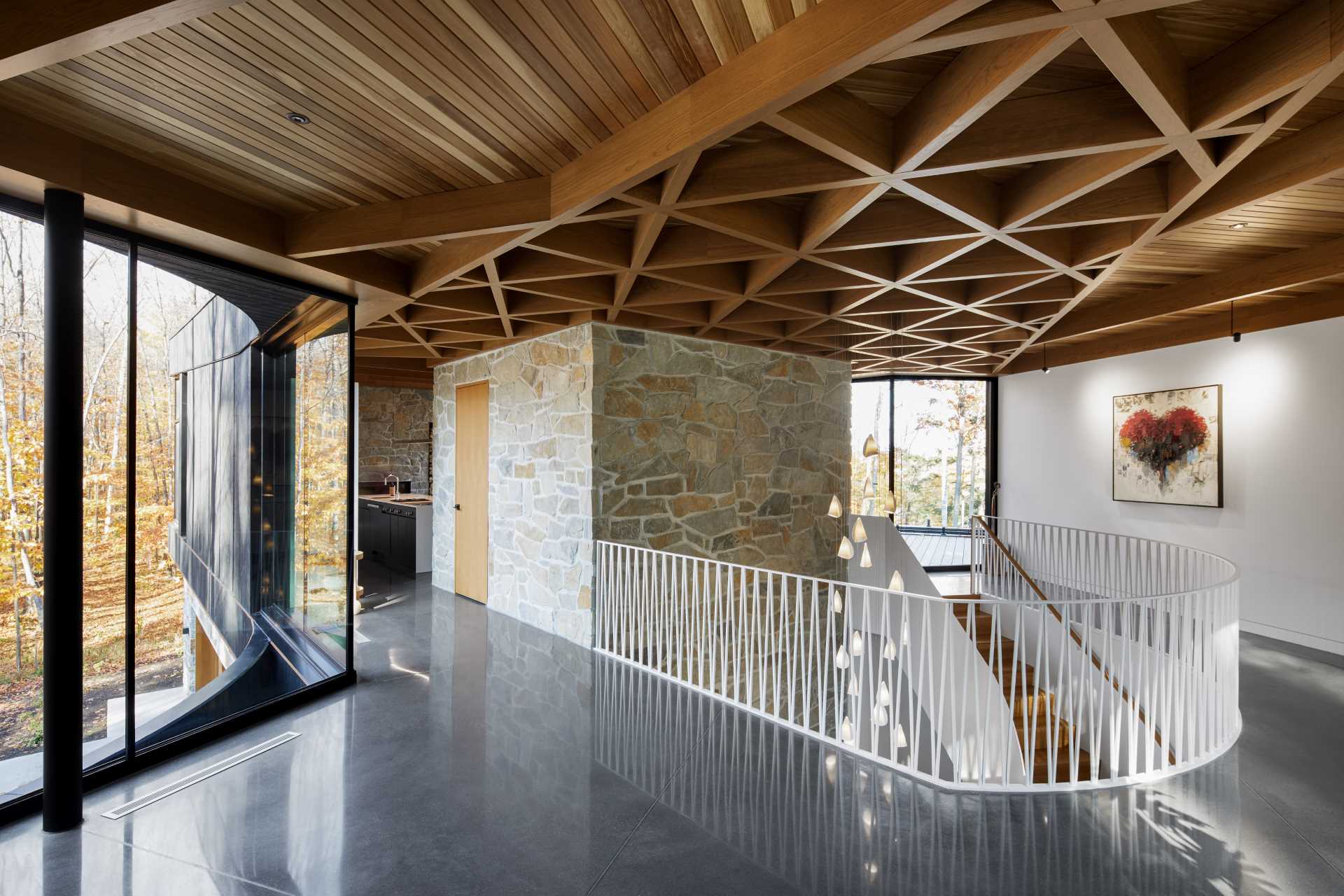 The ceiling of this modern home is covered with knot-free cedar slats, providing a warm and soft contrast to the black exterior. The cedar ceiling also extends outside into a screened room, accentuating the transparent effect.