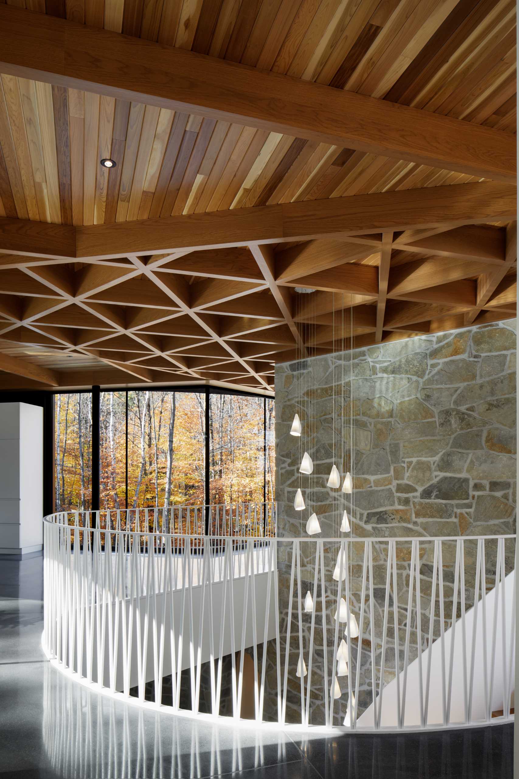 The ceiling of this modern home is covered with knot-free cedar slats, providing a warm and soft contrast to the black exterior. The cedar ceiling also extends outside into a screened room, accentuating the transparent effect.