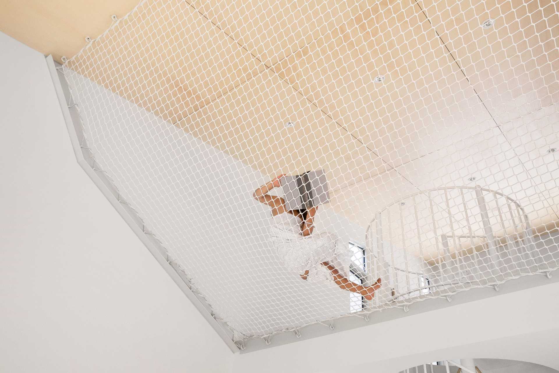 The mezzanine level includes a hammock-like netting, a plywood ceiling, and a secondary living area.