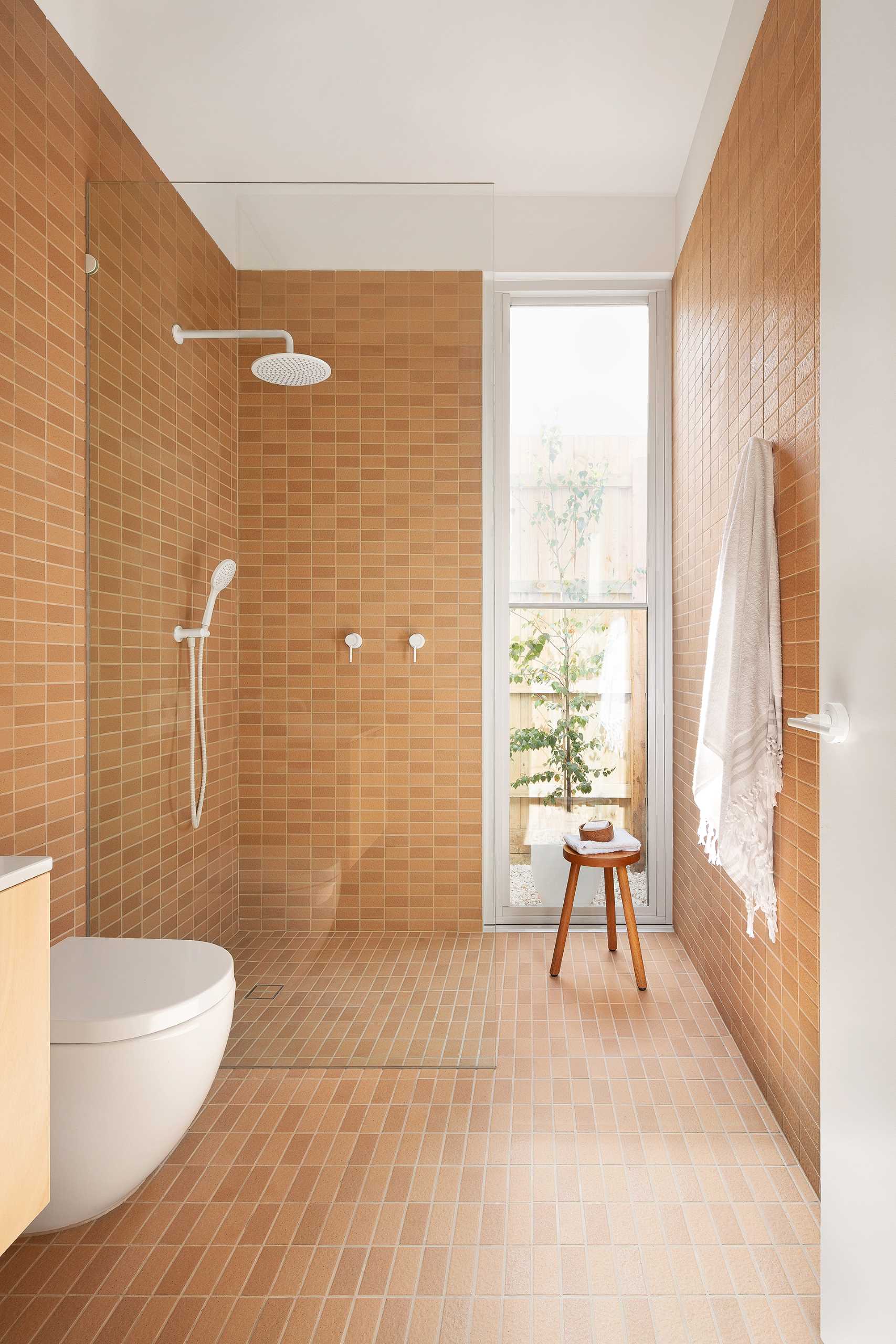 In this modern bathroom, textural Japanese tiles in a terracotta color were chosen to reflect an earthiness, while the crisp white fixtures add freshness, lightness, and a contrasting element.