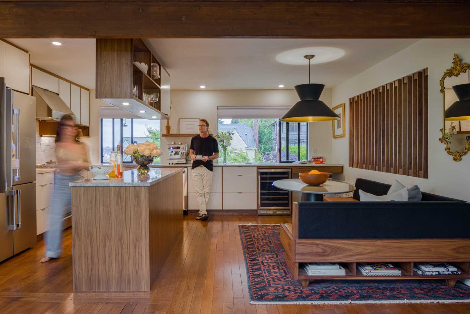 A remodeled kitchen with white cabinets and walnut details that match the dining area.