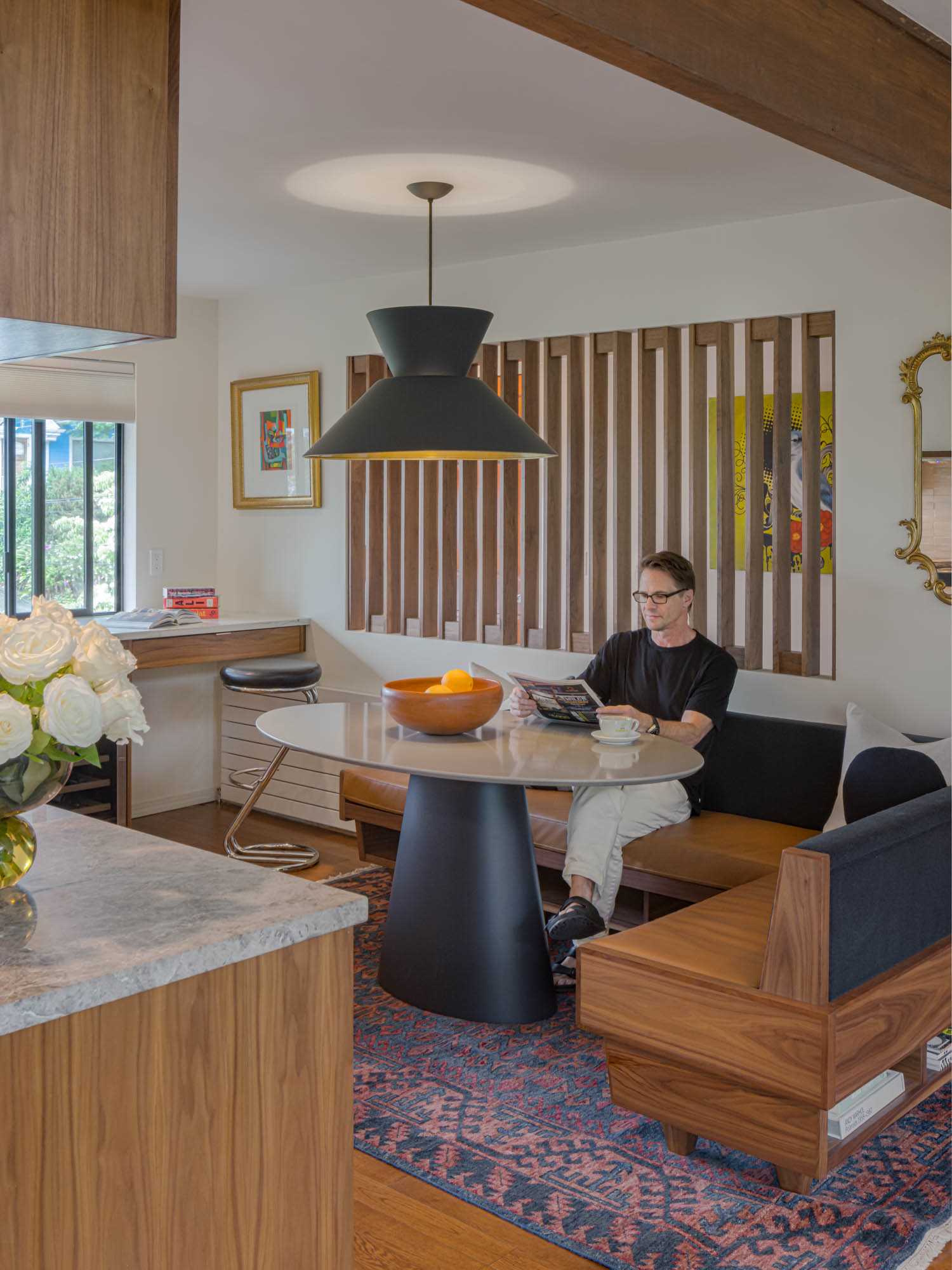 A modern dining area with custom banquette seating and a walnut screen.