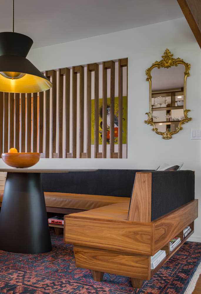 A modern dining area with custom banquette seating and a walnut screen.