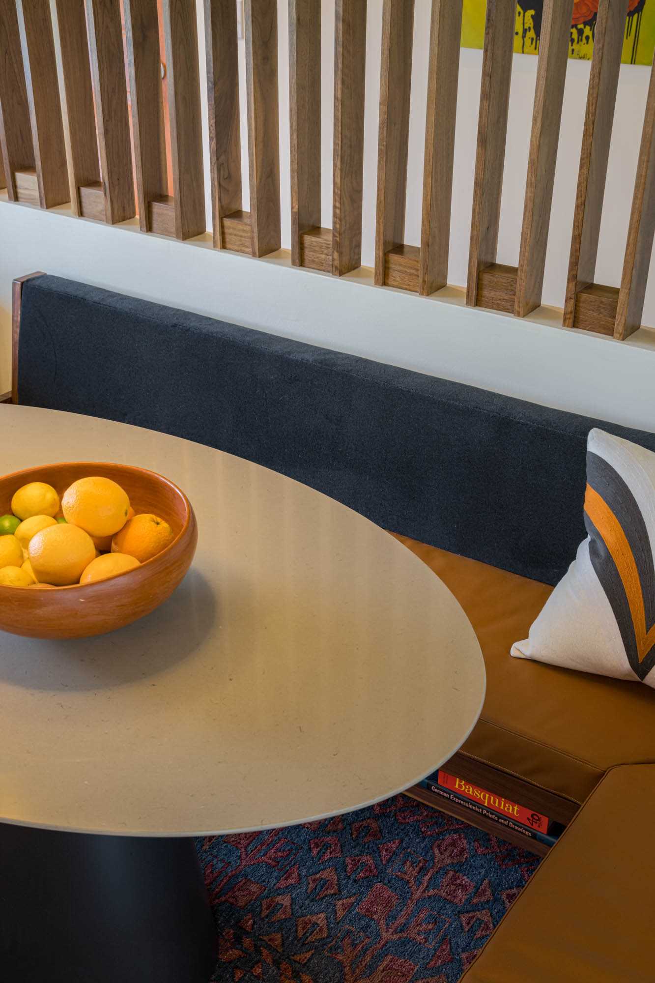 A modern dining area with custom banquette seating and a walnut screen.