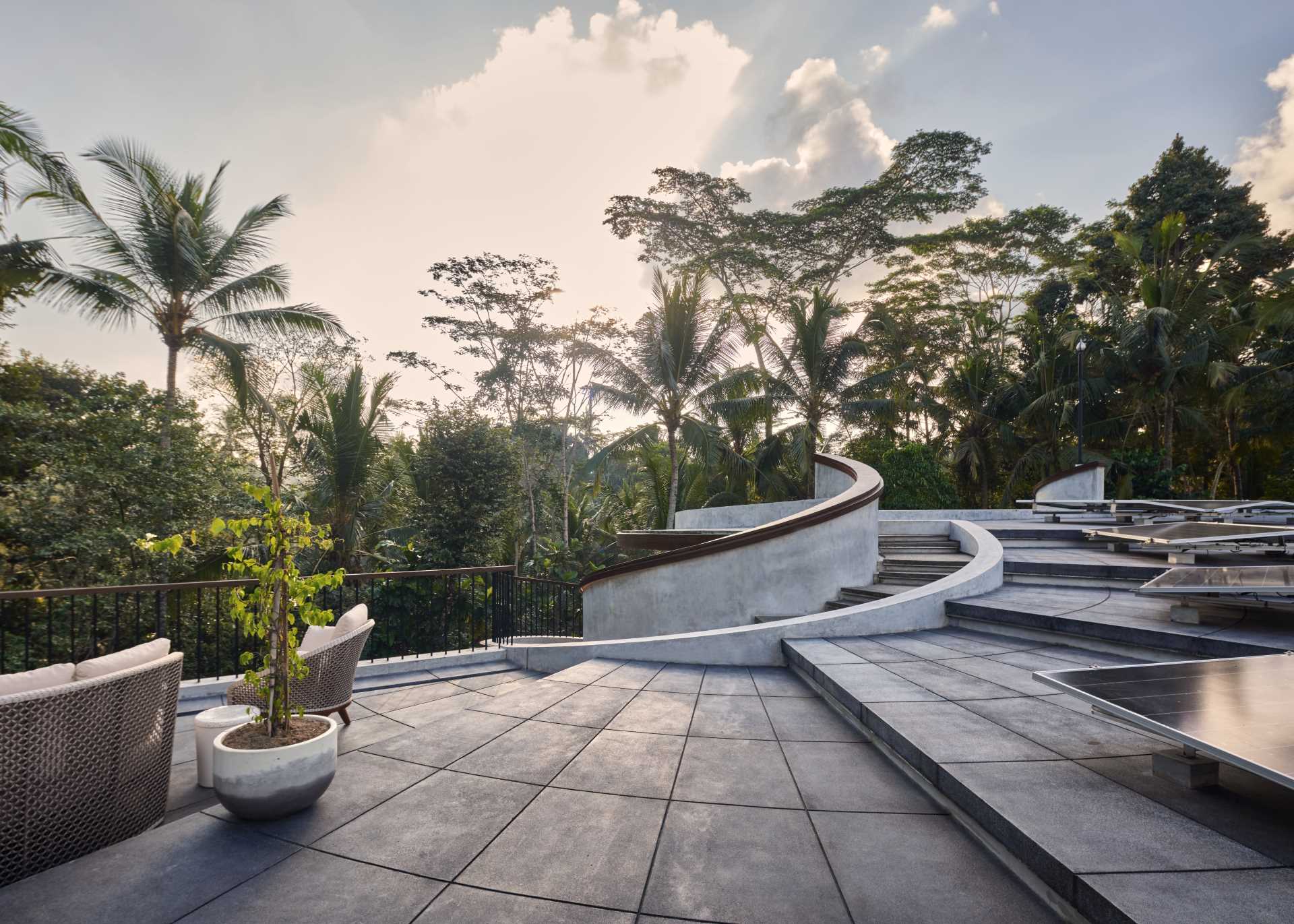 A modern home with spiral stairs that lead to the roof, where solar panels and sitting areas can be found.