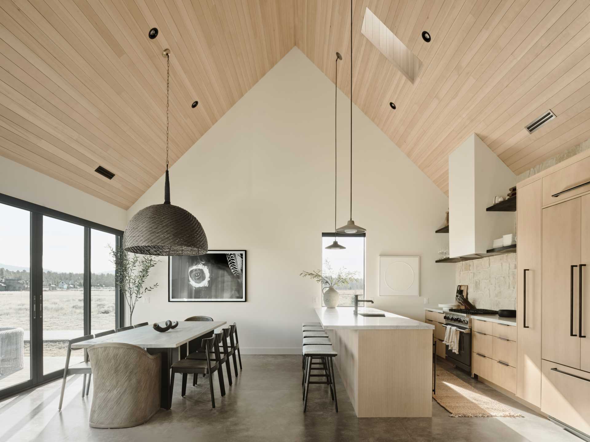 The open-plan great room is also home to the dining area and kitchen. In the kitchen, a stone wall provides a backdrop for the stove and open shelving.