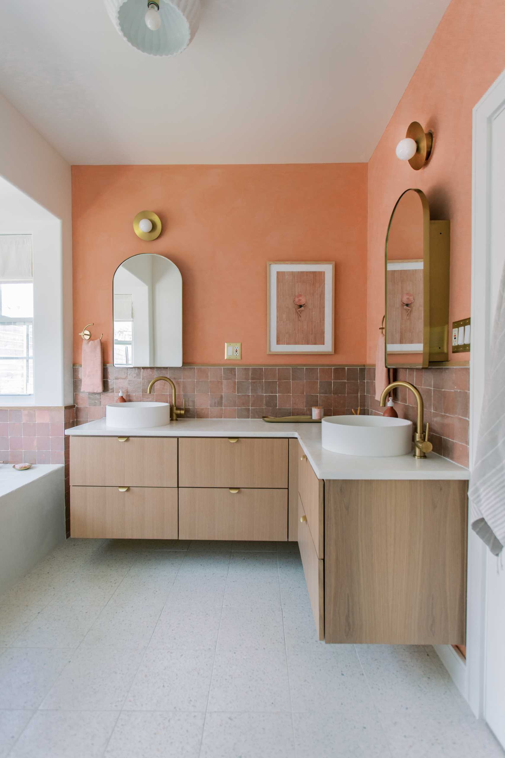 A contemporary bathroom renovation received a new corner vanity with double sinks, new tiles, and colorful walls.