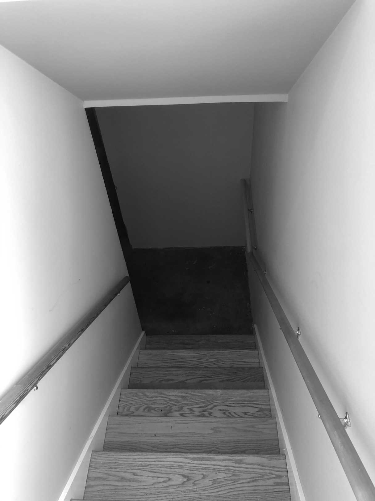 BEFORE - The original basement stairs, located by the front door, had wood treads and matching wood handrails.