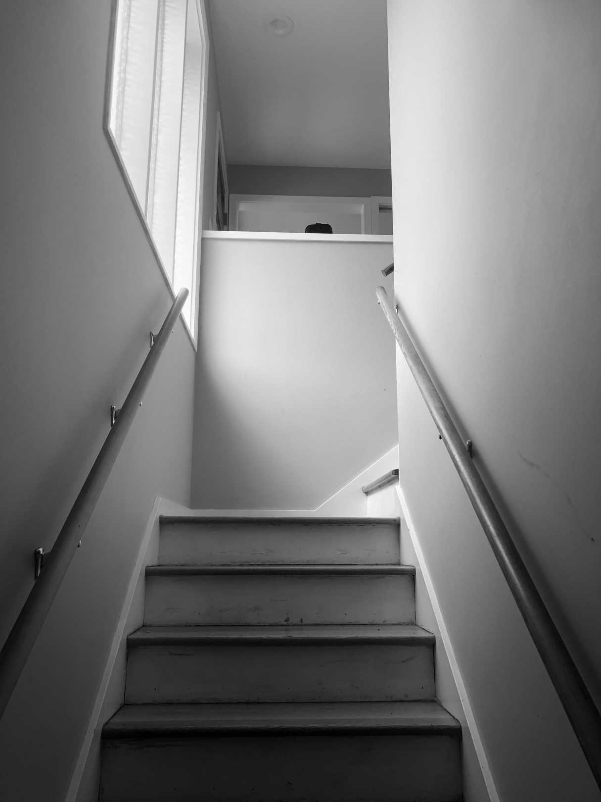 BEFORE - The original basement stairs, located by the front door, had wood treads and matching wood handrails.