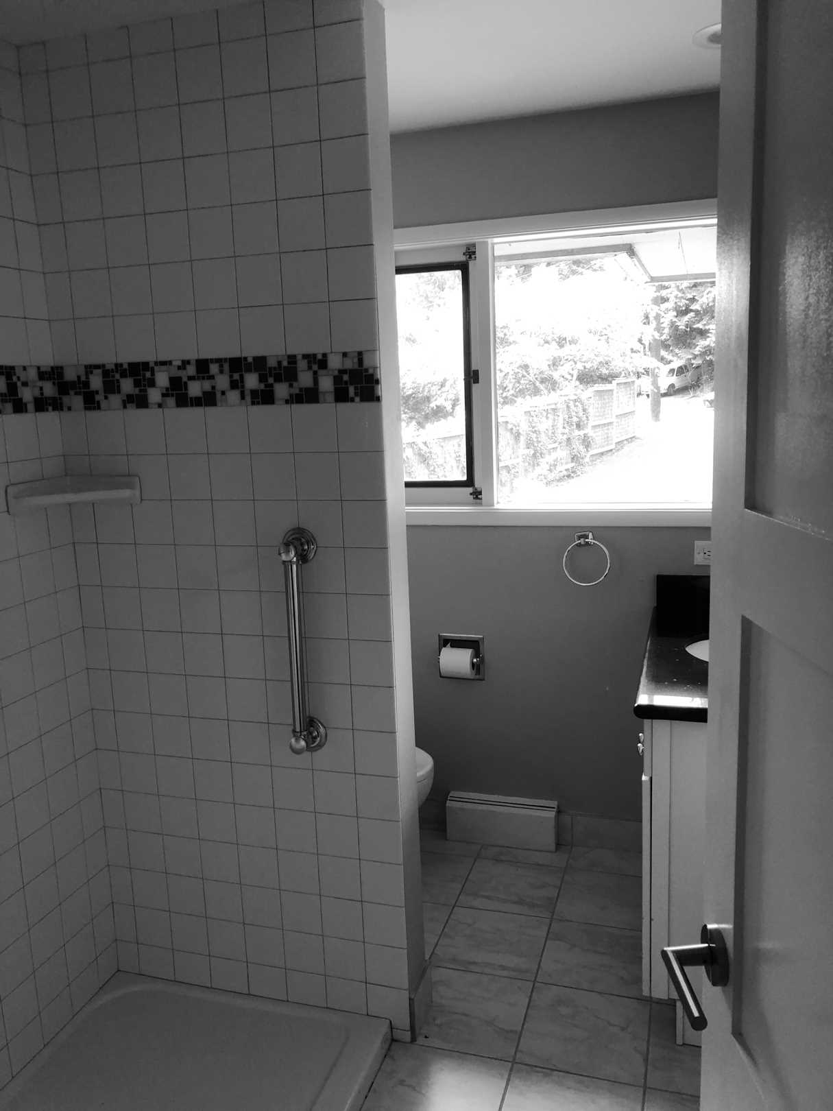 Before - The original bathroom had a small vanity with the toilet by the window, and a shower wall blocking the natural light.