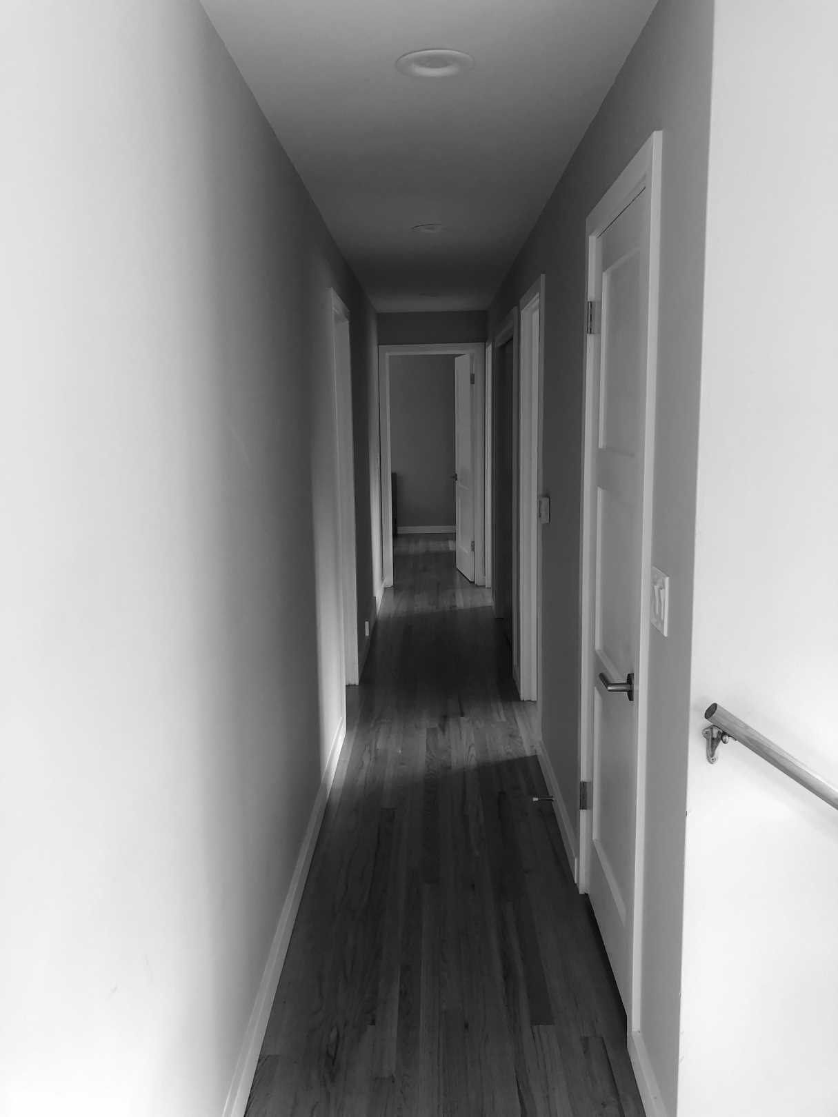 Before - The original hallway was dark and plain, with doors to a bedroom and bathrooms.