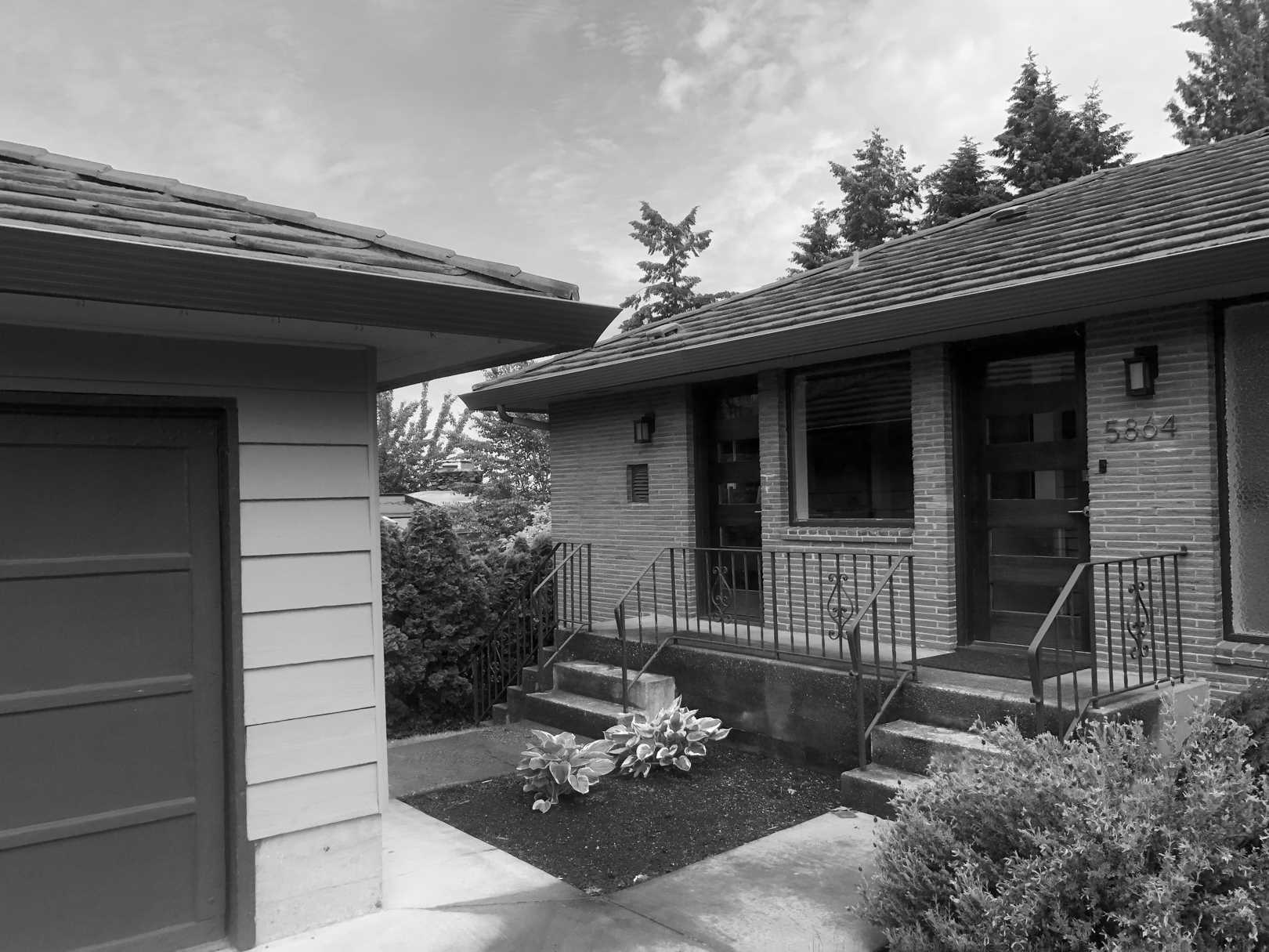 Before - This dated single-story, mid-century home had two doors at the front of the home, with steps leading to each one.