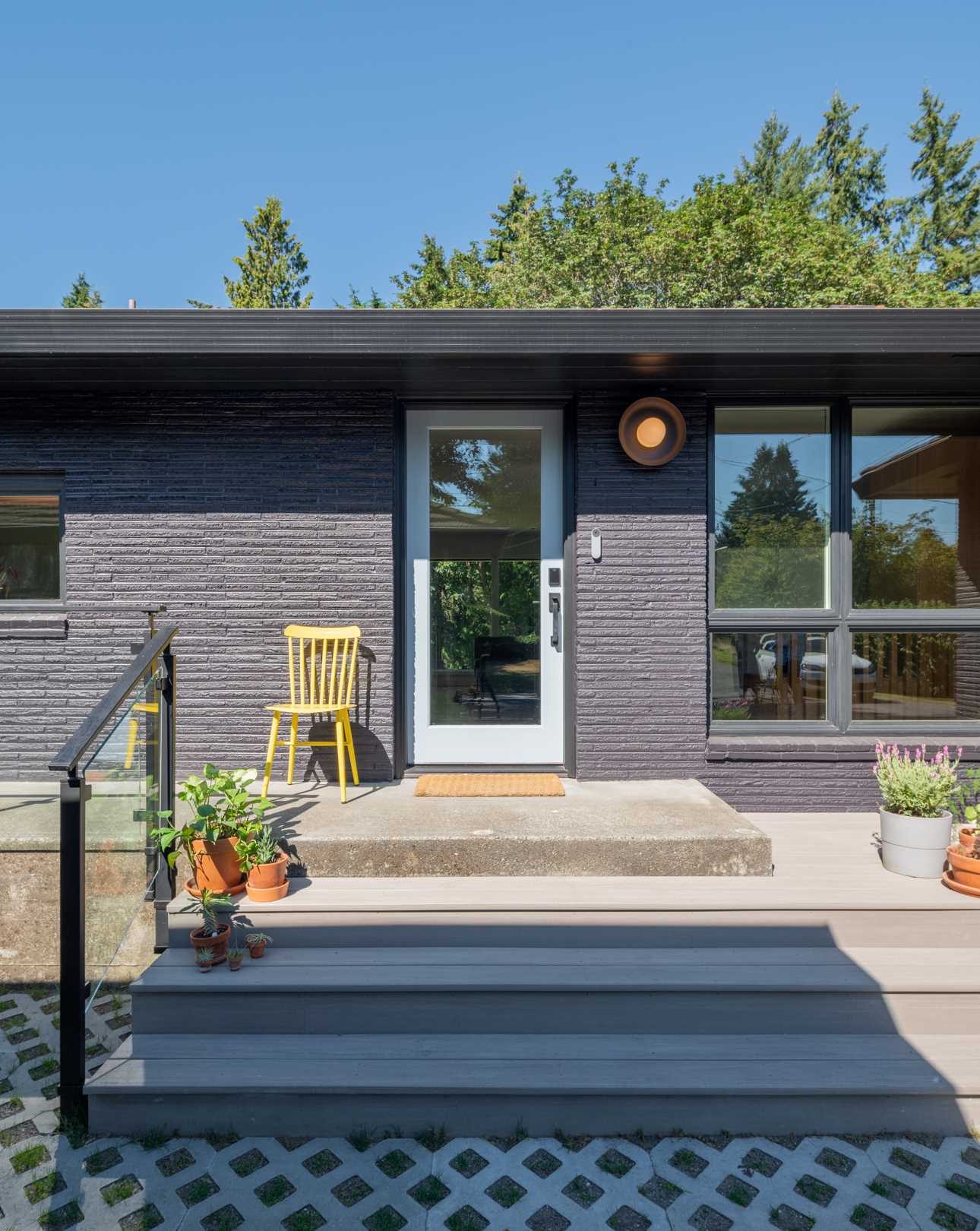 This updated facade has been opened up, with wide steps leading to a single front door. The exterior has been painted and potted plants have been added.