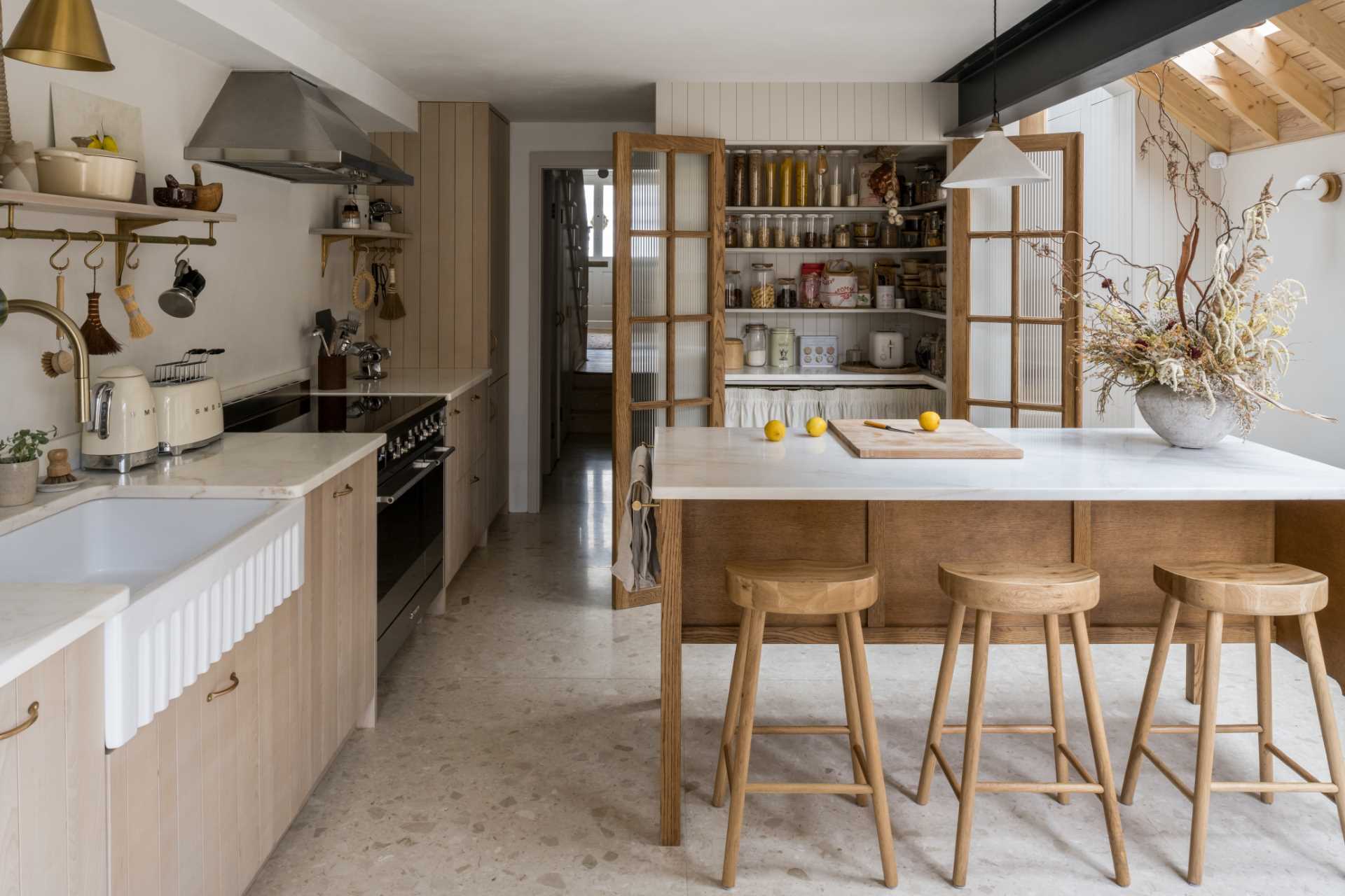 In this kitchen, the pantry doors open directly out onto the multi-functioning marble-topped preparation island.