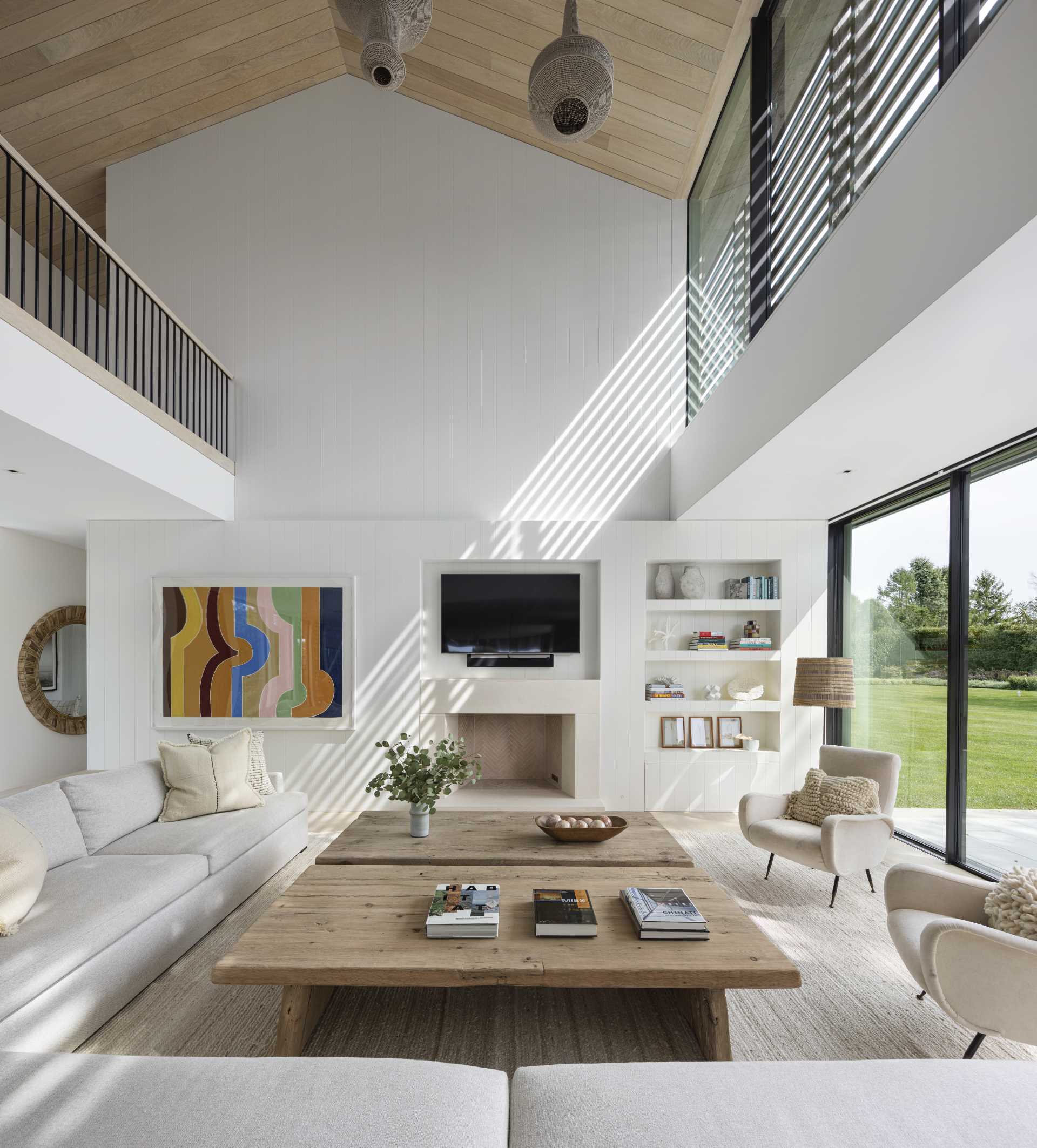 A contemporary living room with double-height ceiling and a wall with niches for the TV and decor.