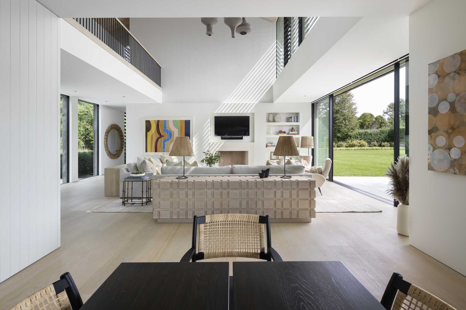 A contemporary living room with double-height ceiling and a wall with niches for the TV and decor.