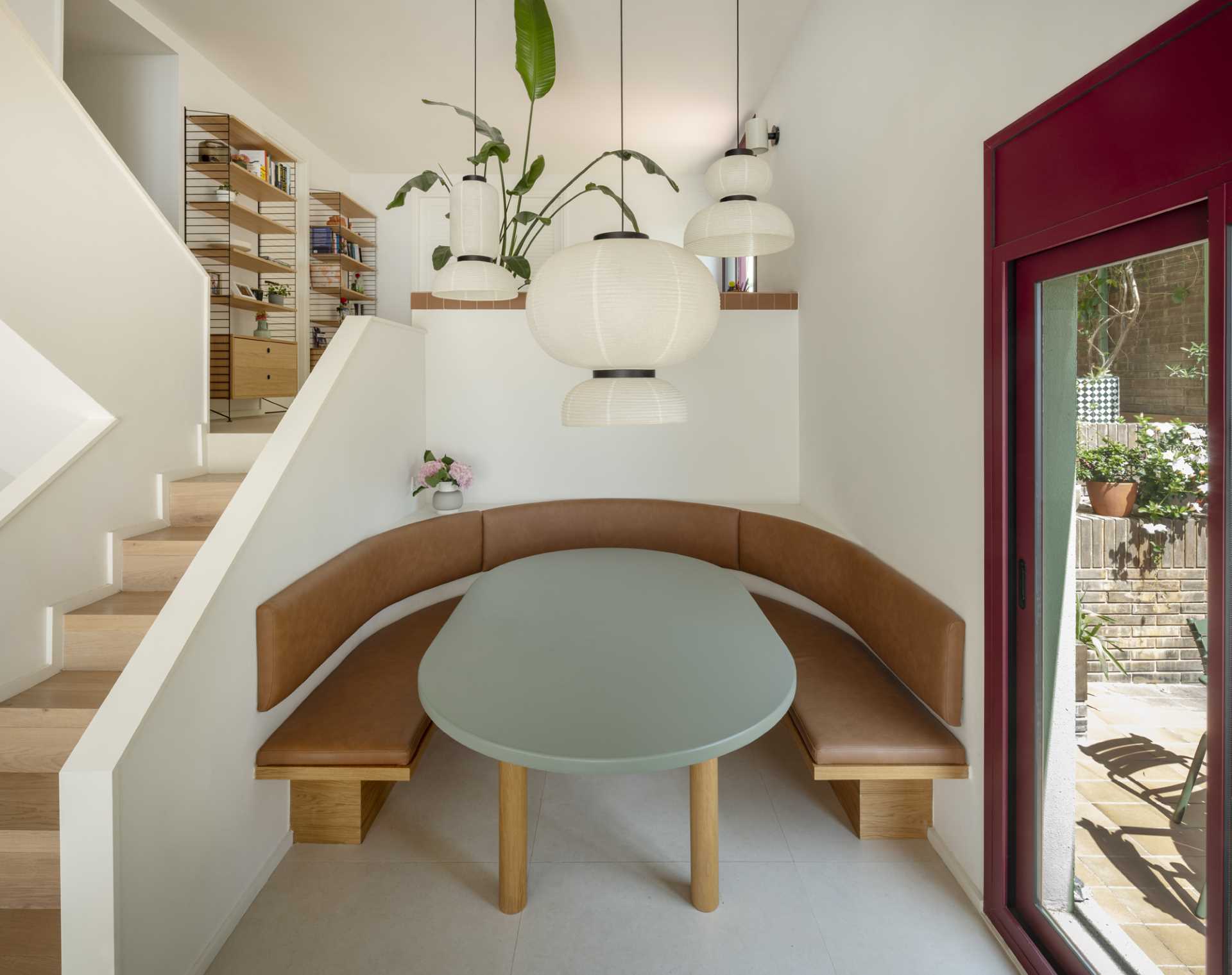 This modern dining area is tucked away in a nook with a built-in banquette that lines the curve of the space, and a trio of pendant lights hanging above.