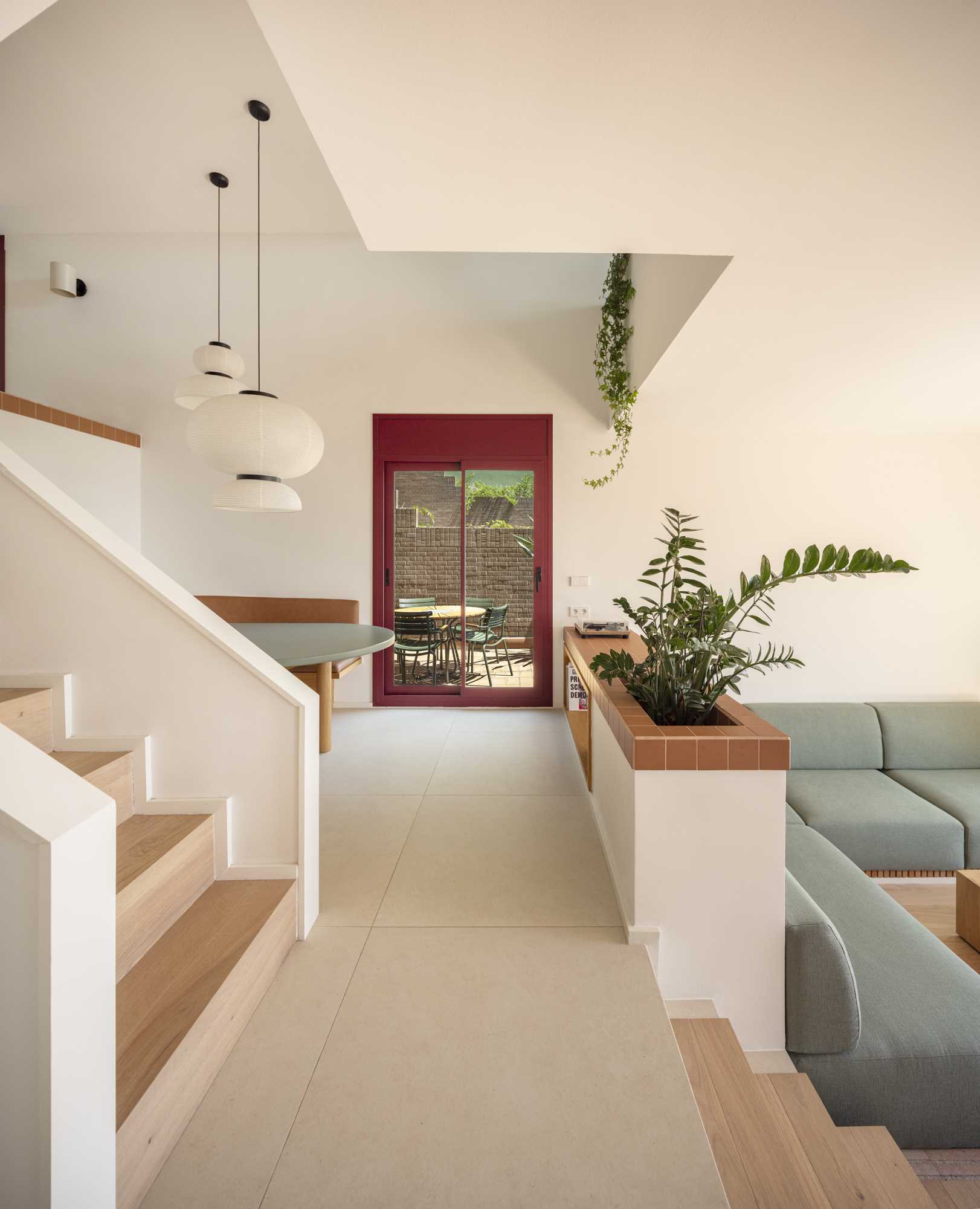 This modern dining area is tucked away in a nook with a built-in banquette that lines the curve of the space, and a trio of pendant lights hanging above.