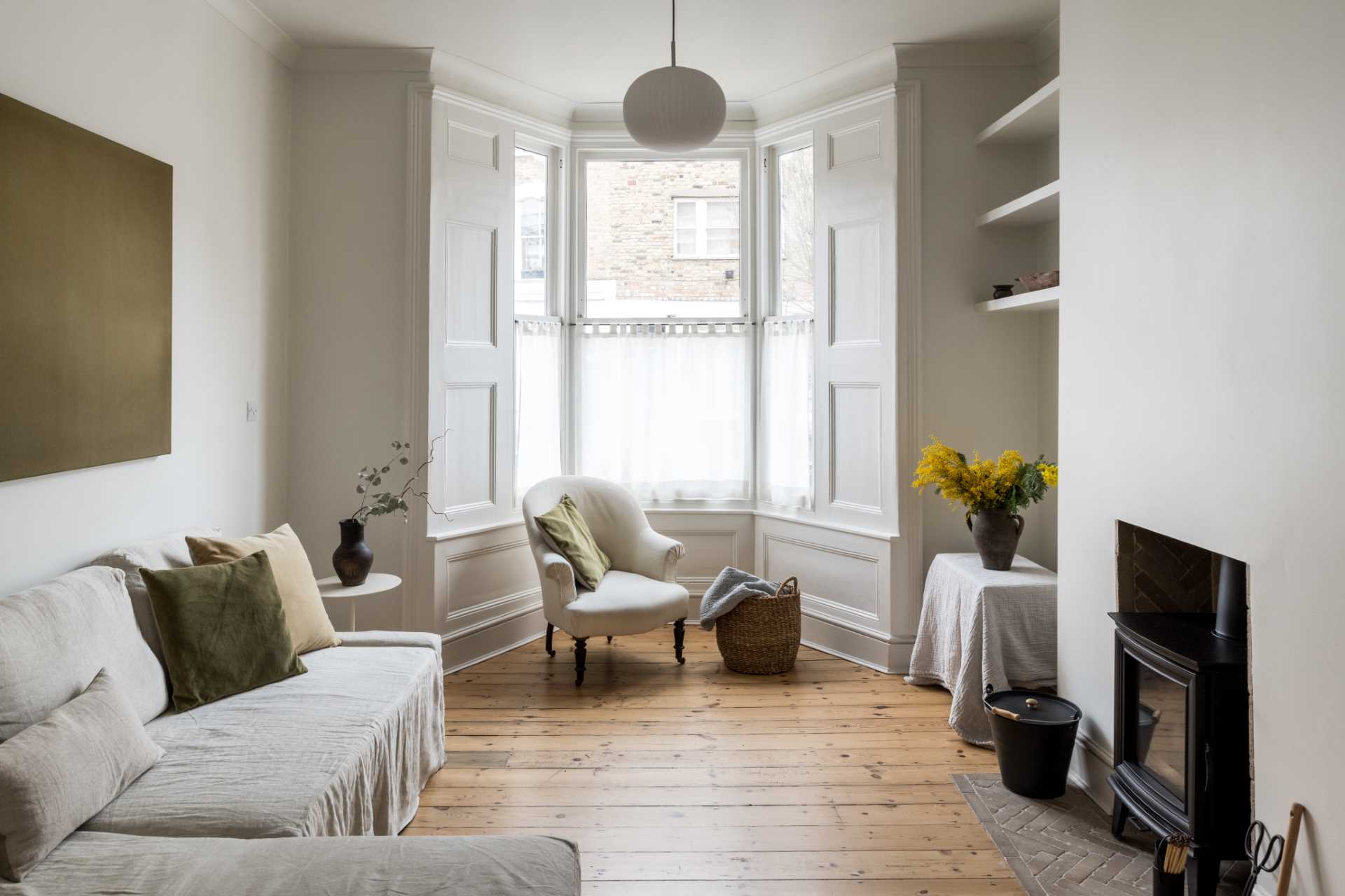 A renovated living room retained original elements, like the fireplace and bay window.