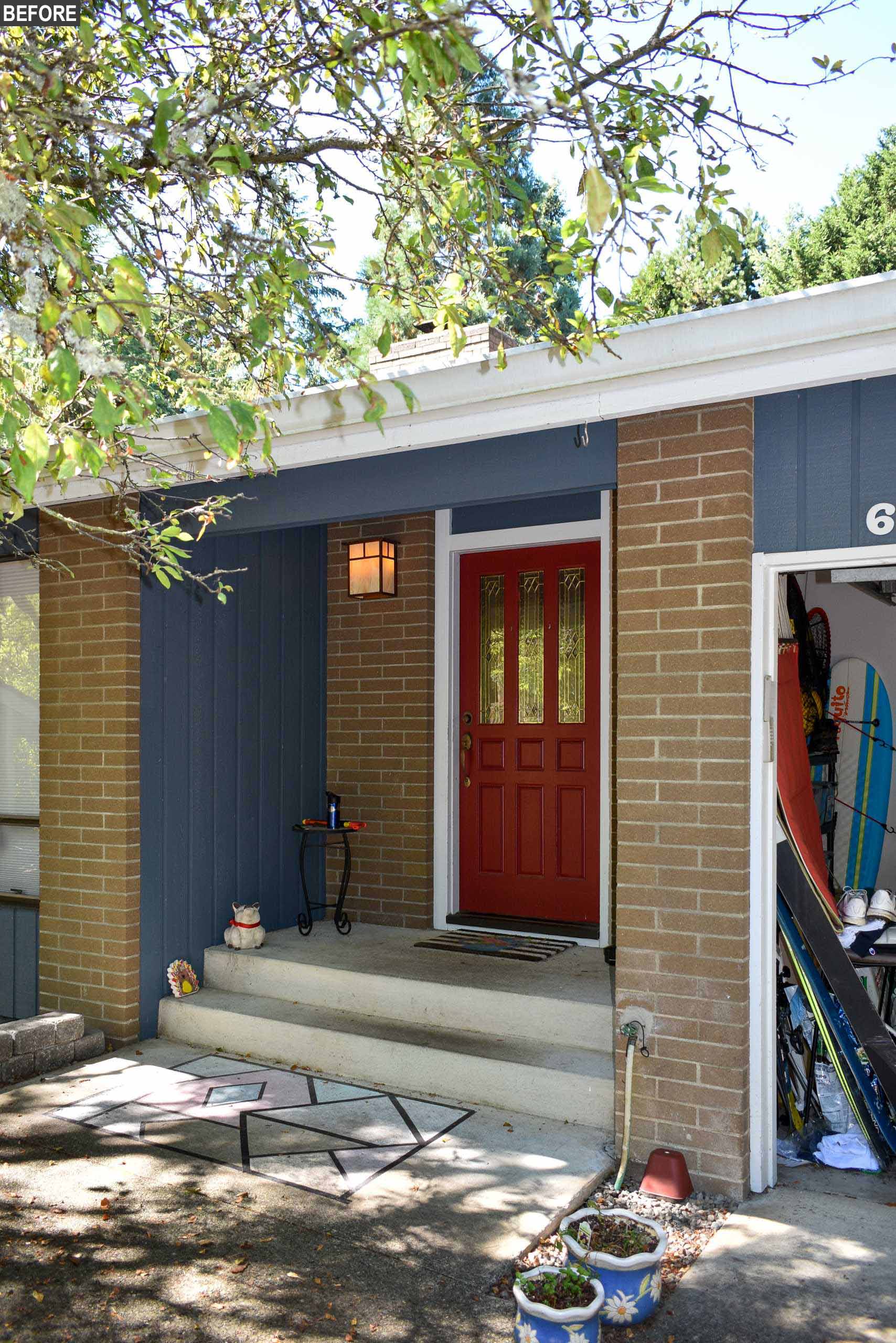 Before remodel - The original entryway had blue vertical siding, concrete steps, and a red front door.